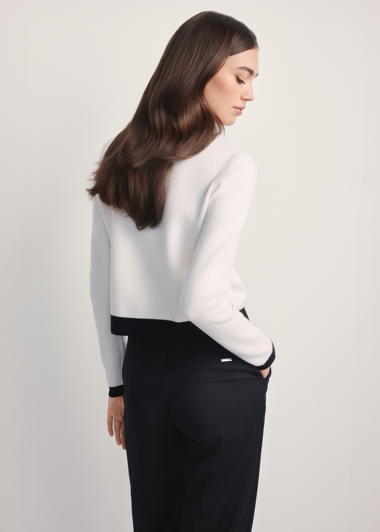 Biały kardigan damski KARDT-0053-12(Z25), widok produktu z tyłu na modelce. Widoczna połowa sylwetki. 