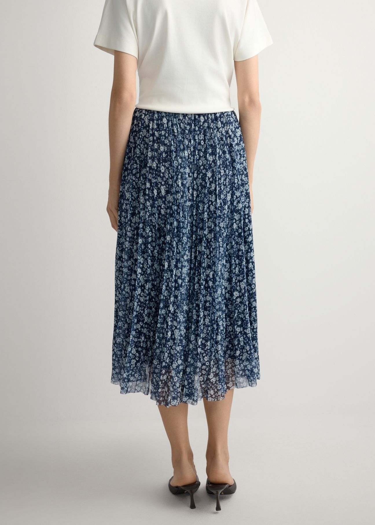 Spódnica plisowana midi w kwiaty SPCDT-0110-7P(W26), widok produktu z tyłu na modelce. Widoczna połowa sylwetki.