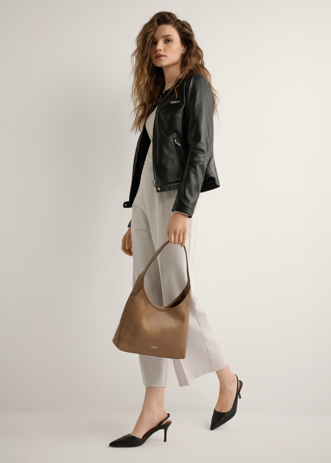 Camelowa średnia torebka damska TOREC-1200-1D(W26), widok produktu w dłoni modelki. Widoczna cała sylwetka.