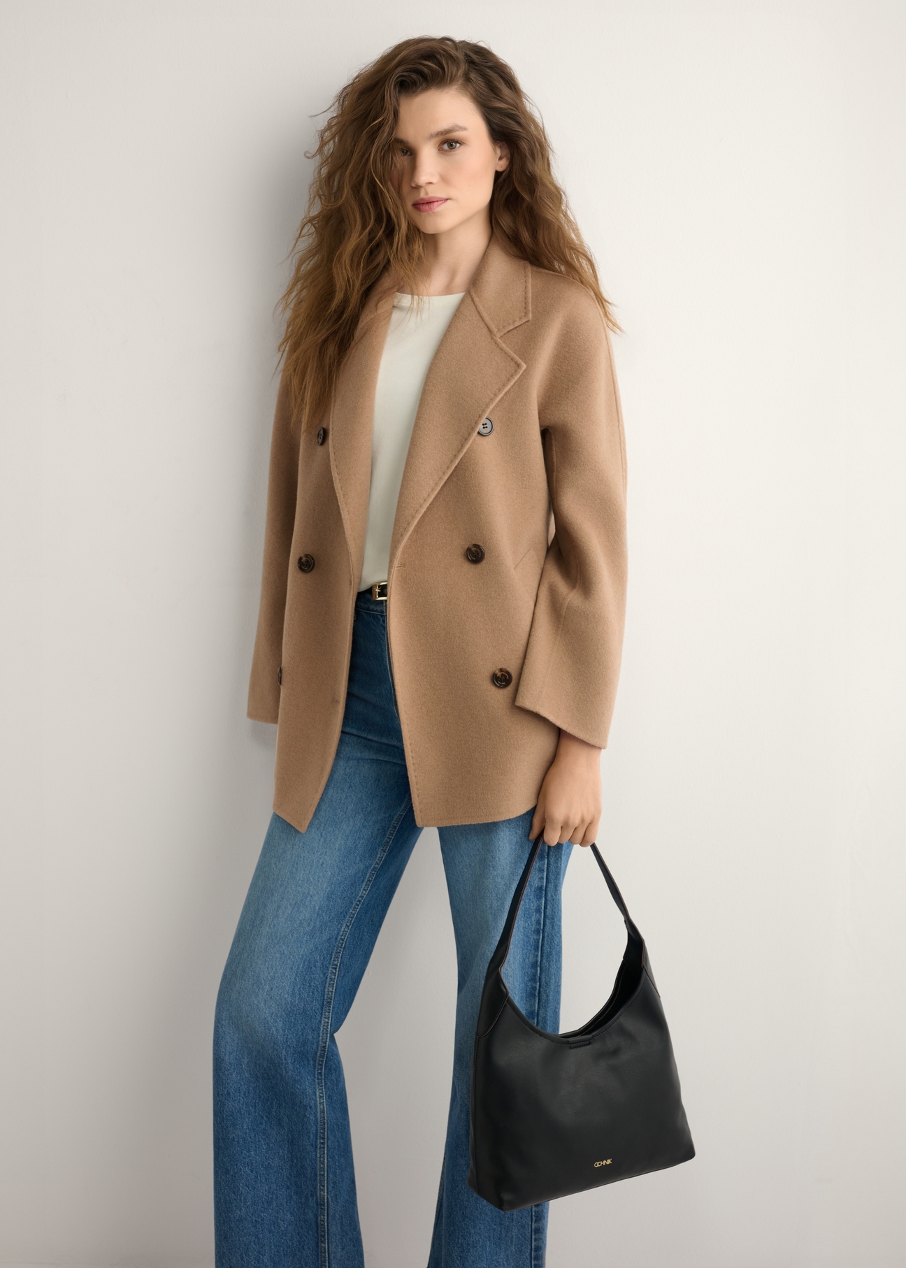 Czarna średnia torebka damska TOREC-1200-99(W26), widok produktu w dłoni modelki. Widoczna połowa sylwetki.