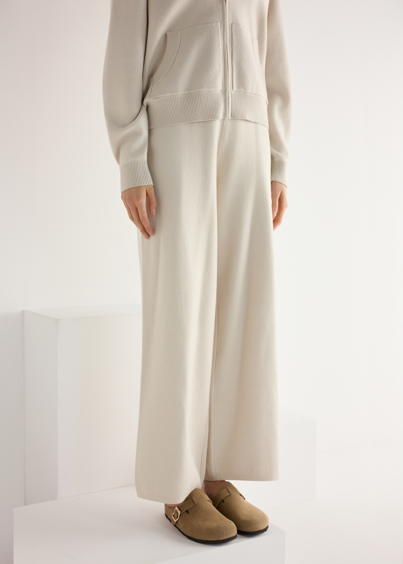 Zamszowe klapki damskie w kolorze chłodnego beżu BUTYD-1267-1K(W26), widok produktu skosem na stopach modelki.