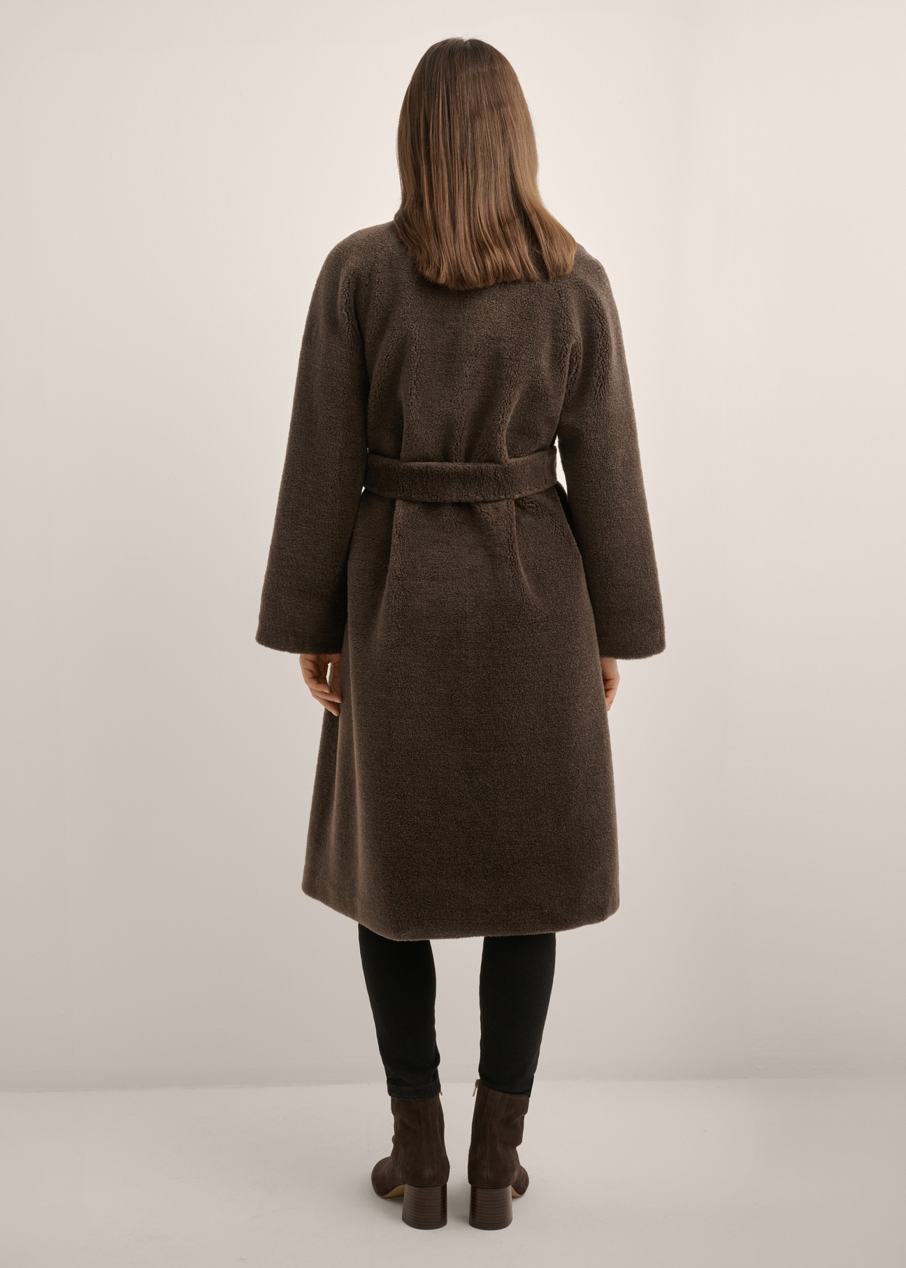 Brązowe wełniane futro damskie FUTDW-0041-1I(Z26), widok produktu od tyłu na modelce. Widoczna cała sylwetka.