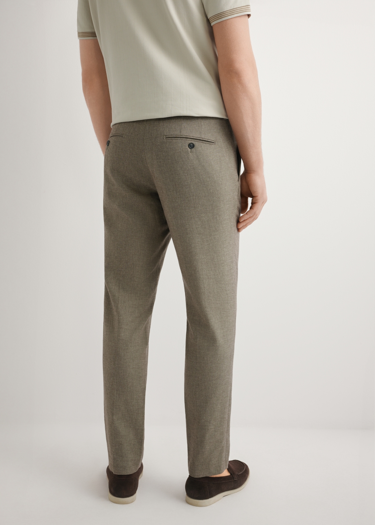 Ciemnobrązowe spodnie garniturowe męskie SPOMT-0098-1I(W26), widok produktu z tyłu na modelu. Widoczna połowa sylwetki.