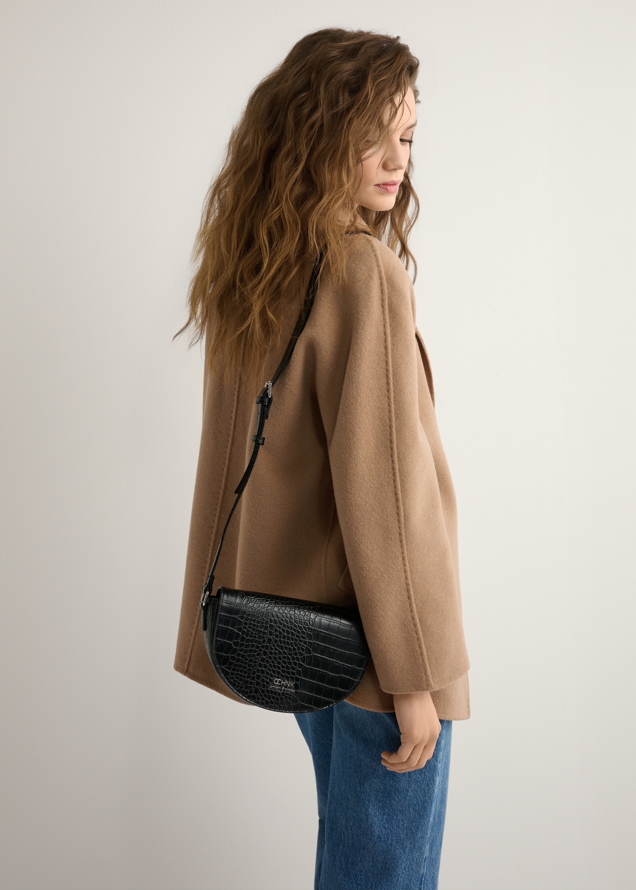Czarna półokrągła listonoszka damska croco TOREC-1184-9G(W26), widok produktu na ramieniu modelki. Widoczna połowa sylwetki.