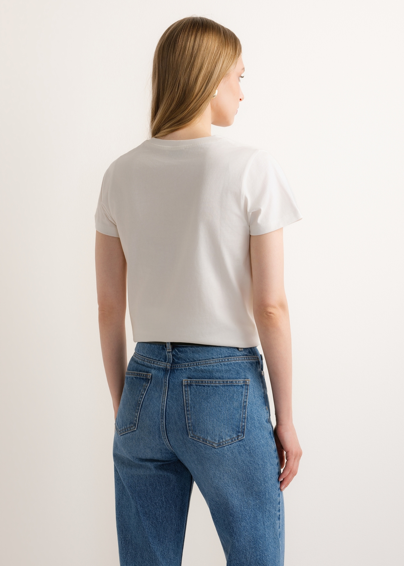 Kremowy t-shirt damski z nadrukiem TSHDT-0166-0B(Z26) - widok produktu z tyłu, na modelce, na jasnym tle. Widoczna połowa sylwetki.