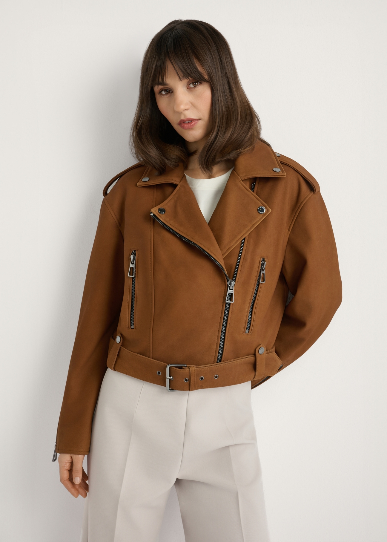 Skórzana kurtka ramoneska w kolorze koniaku KURDS-0610-1F(W26), widok produktu z przodu na modelce. Widoczna połowa sylwetki.