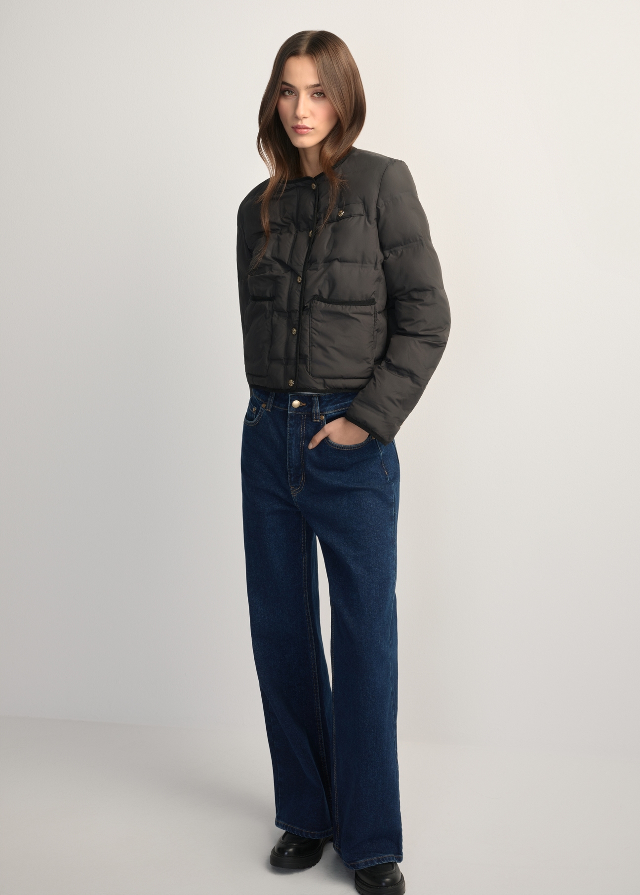 Czarna krótka kurtka damska KURDT-0621-99(W26), widok produktu z przodu na modelce. Widoczna cała sylwetka.