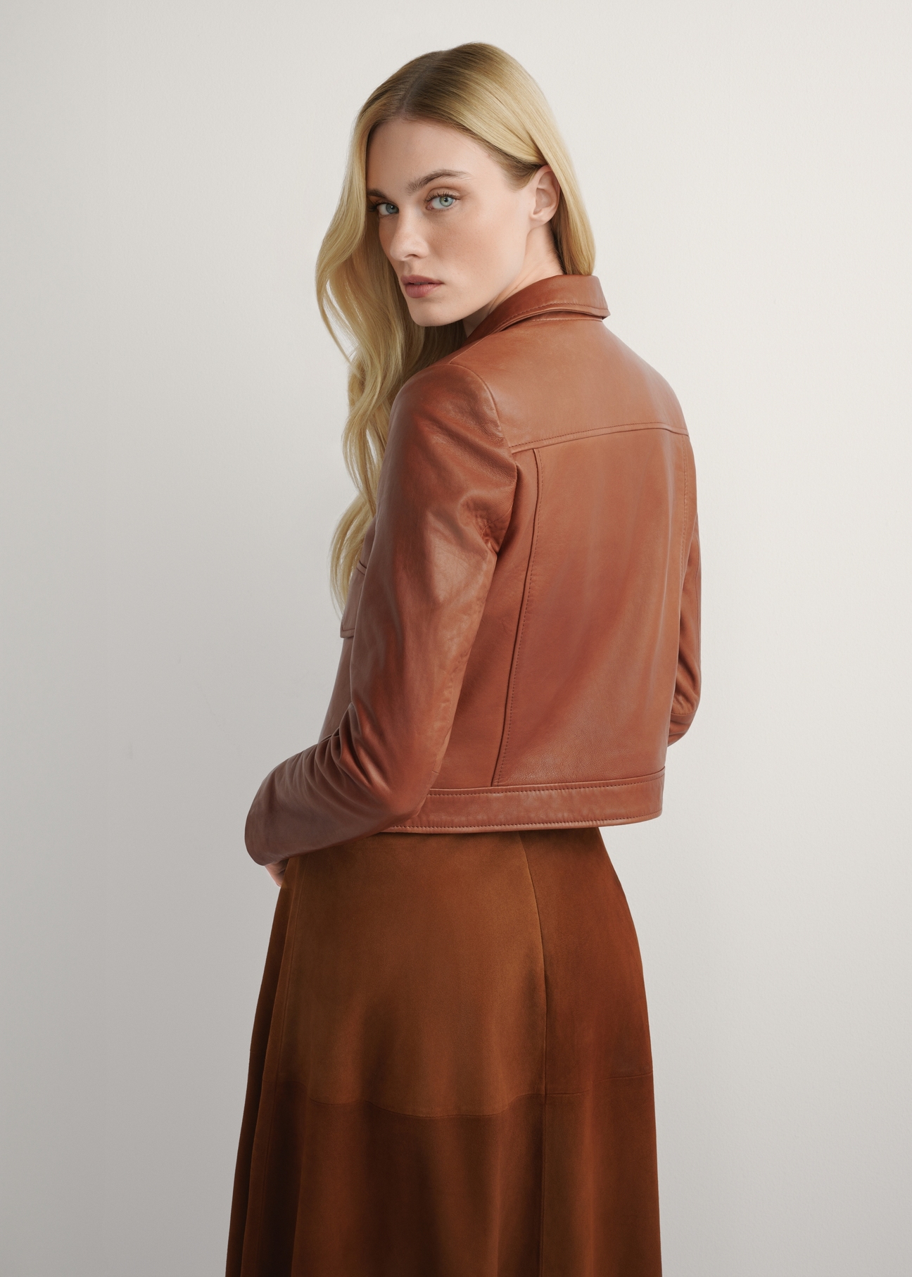 Skórzana krótka kurtka damska w kolorze camelu KURDS-0471-1D(W26), widok produktu z tyłu na modelce. Widoczna połowa sylwetki.