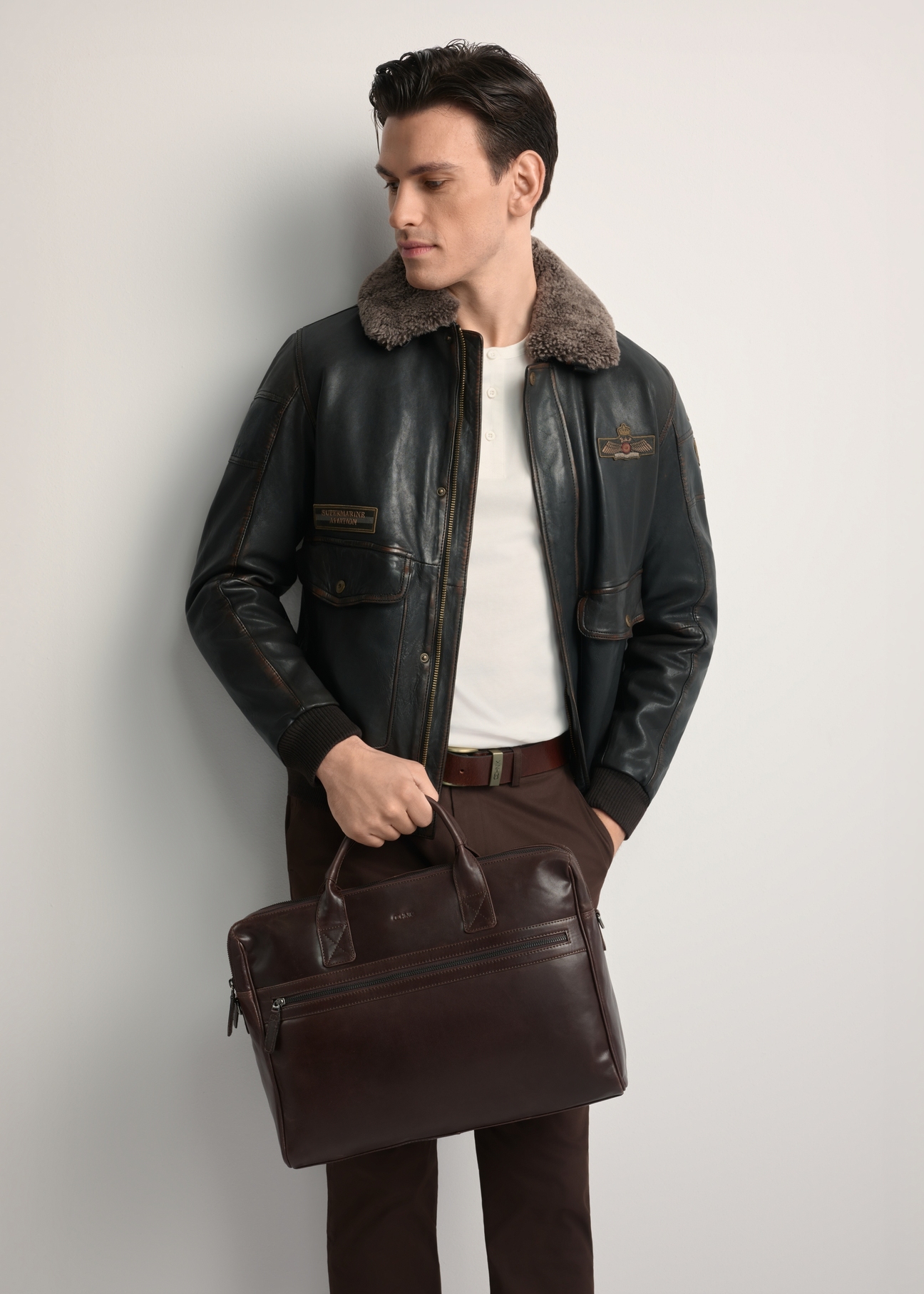 Brązowa skórzana torba męska TORMS-0460-89(Z25) - widok produktu z przodu, trzymanego przez modela w ręku. Widoczna połowa sylwetki.