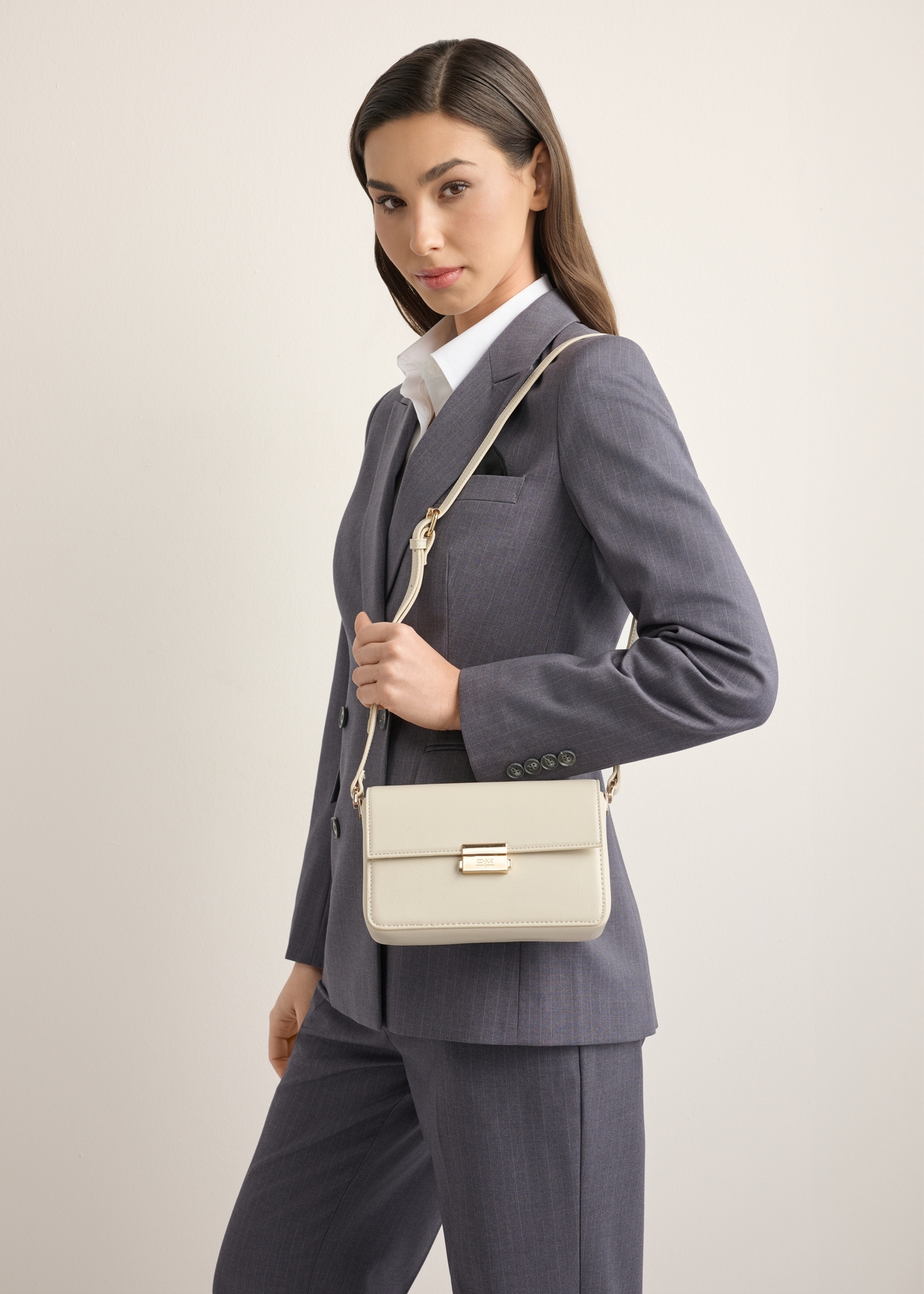 Elegancka kremowa torebka damska TOREC-1251-0B(Z26), widok produktu z przodu na modelce. Widoczna połowa sylwetki. 