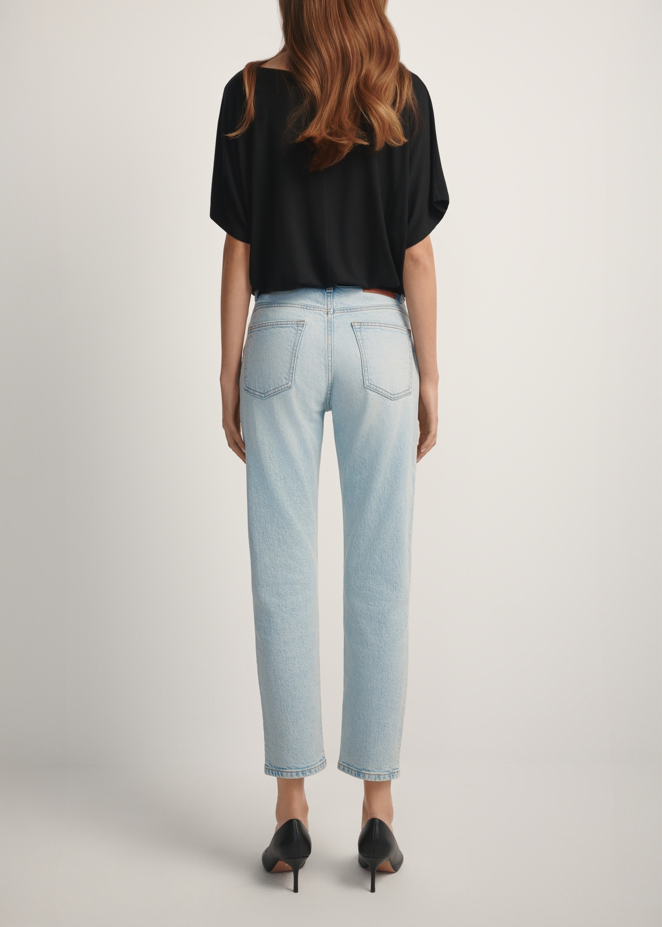 Jasnoniebieskie spodnie jeansowe damskie JEADT-0011-7A(W26), widok produktu z tyłu na modelce. Widoczna połowa sylwetki.