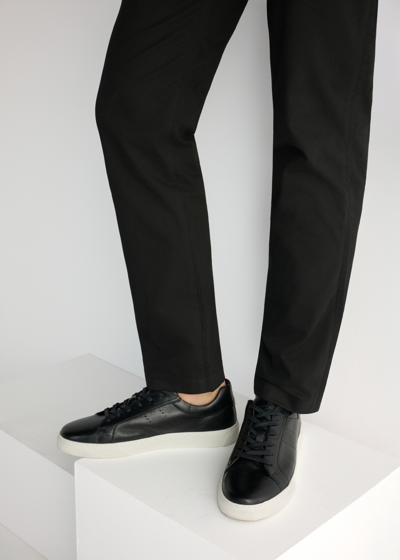 Czarne skórzane sneakersy męskie BUTYM-0486-99(W26), widok produktu od boku na modelu, widoczna połowa sylwetki.