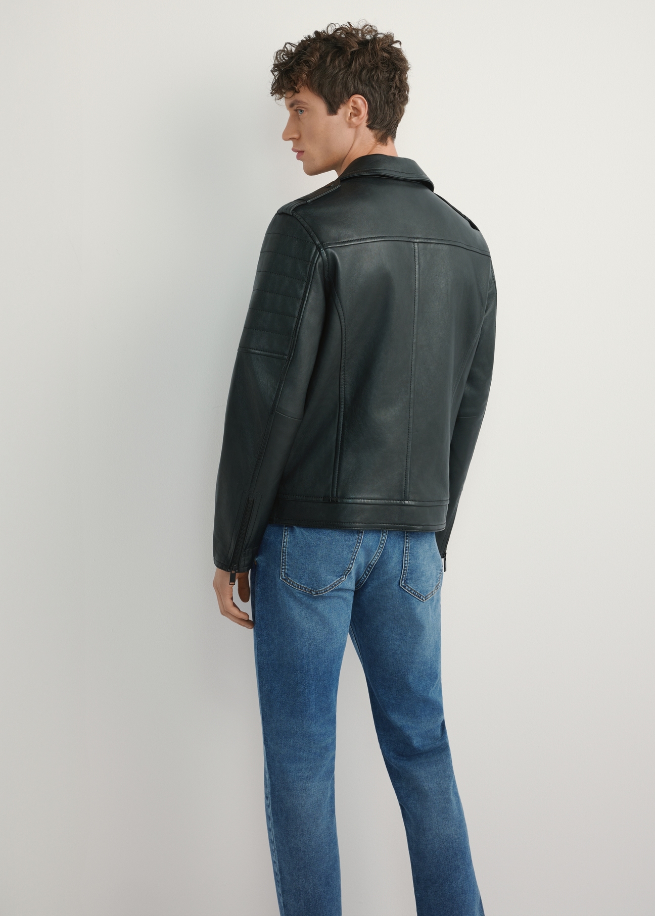 Czarna skórzana kurtka ramoneska męska KURMS-0391-99(W26), widok produktu z tyłu na modelu. Widoczna połowa sylwetki.