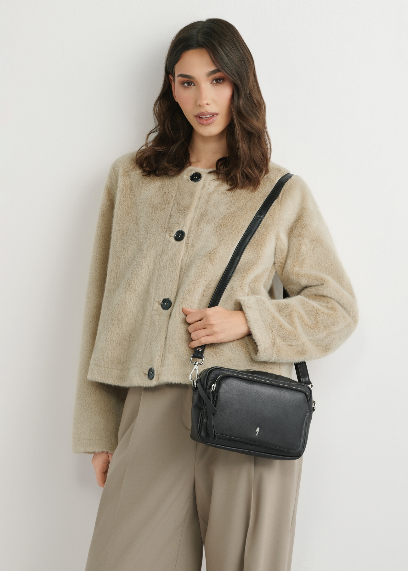 Mała czarna skórzana torebka damska TORES-1023A-99(W26), widok produktu z przodu na ramieniu modelki. Widoczna połowa sylwetki.