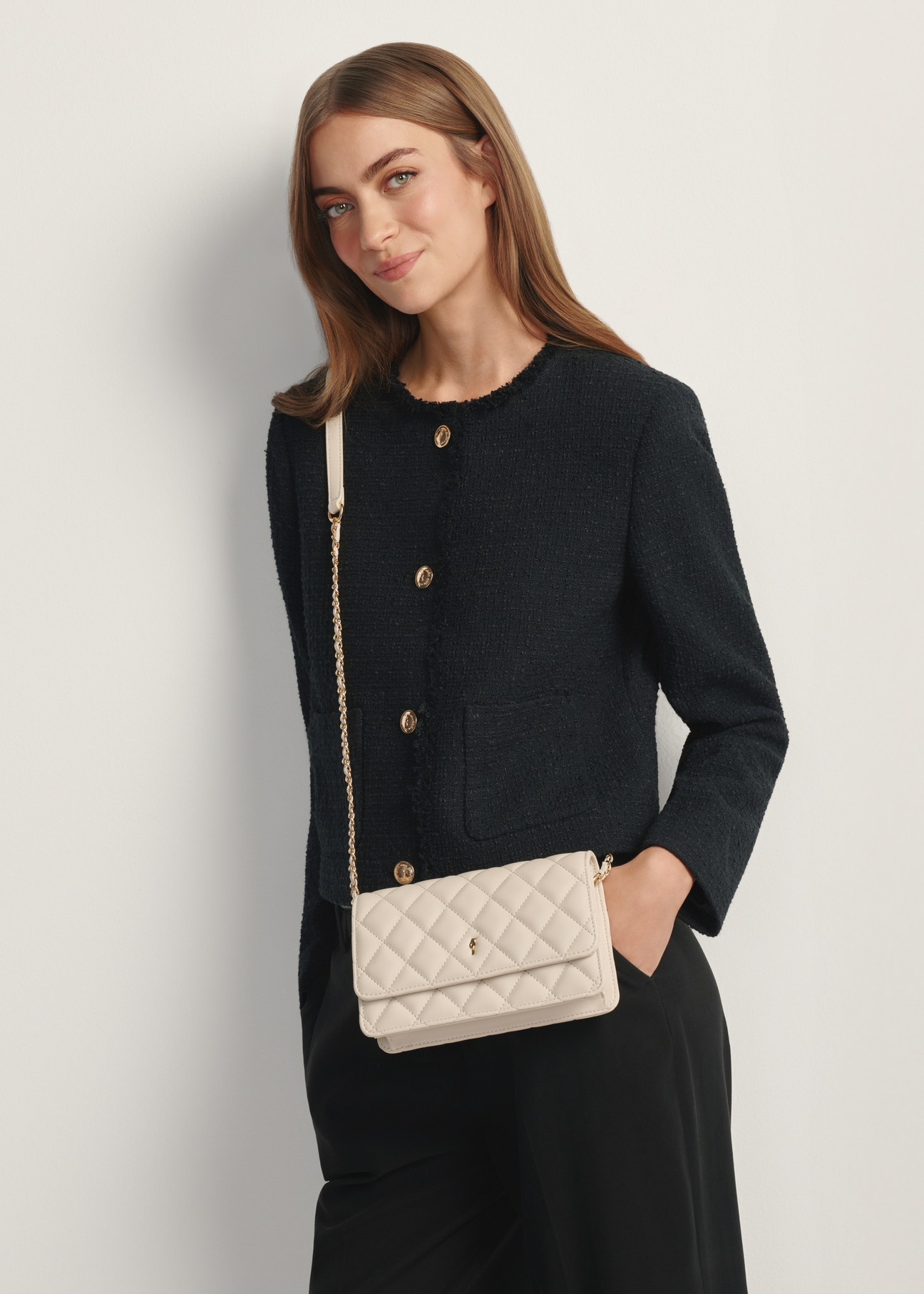 Kremowa mała pikowana torebka damska TOREC-1033-0B(W26), widok produktu na ramieniu modelki. Widoczna połowa sylwetki.