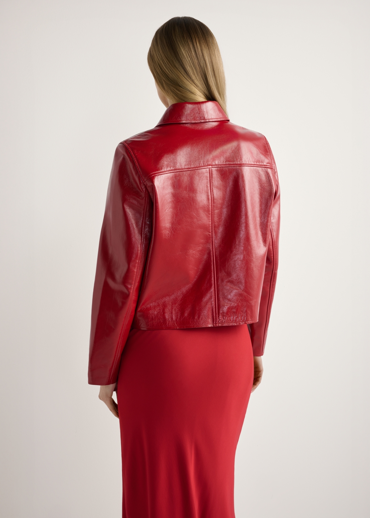 Czerwona krótka kurtka damska KURDS-0612-4B(W26), widok produktu od tyłu na modelce, widoczna połowa sylwetki.