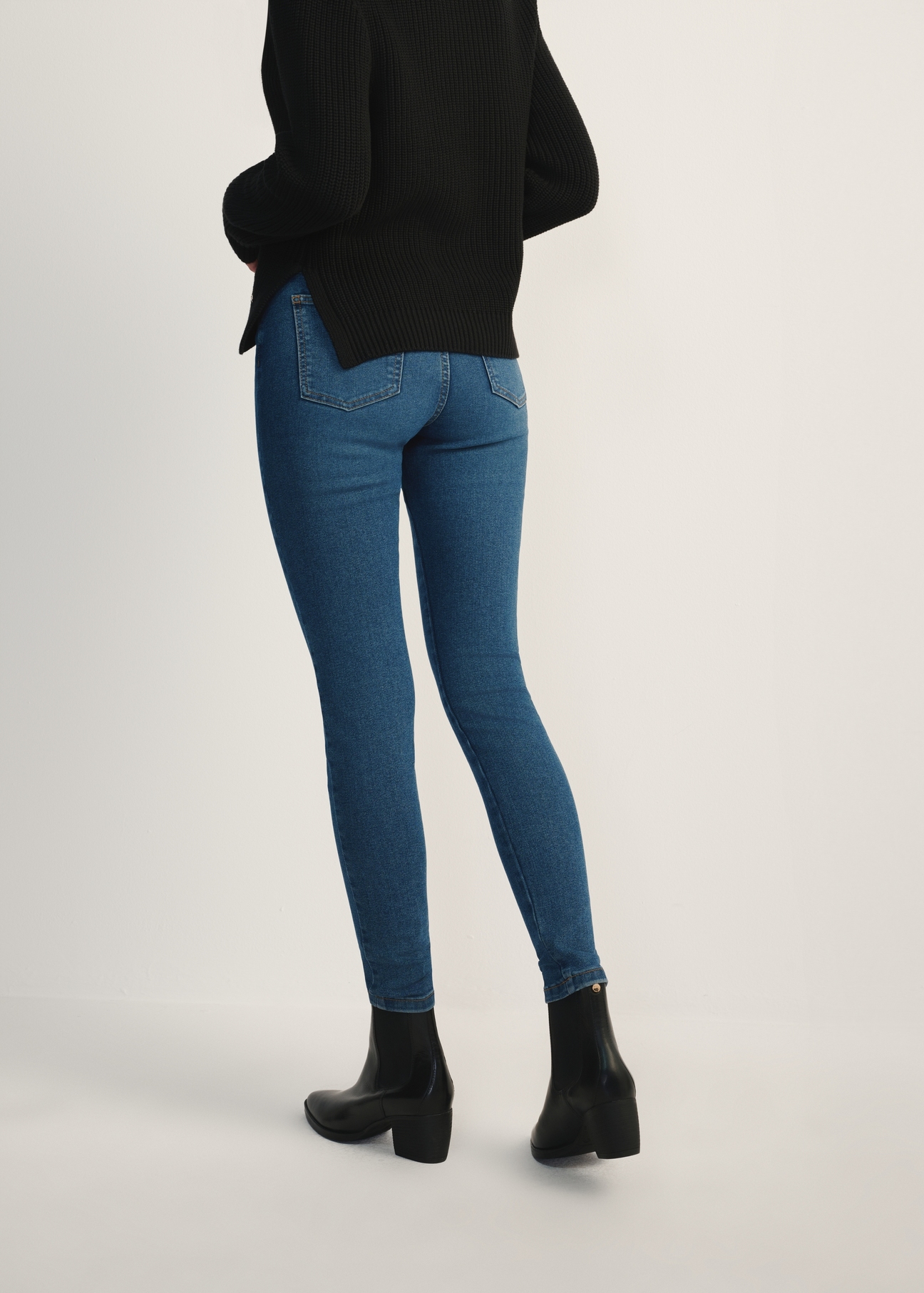 Niebieskie jeansowe spodnie damskie JEADT-0010A-61(Z25), widok produktu od tyłu na modelce, widoczna połowa sylwetki.