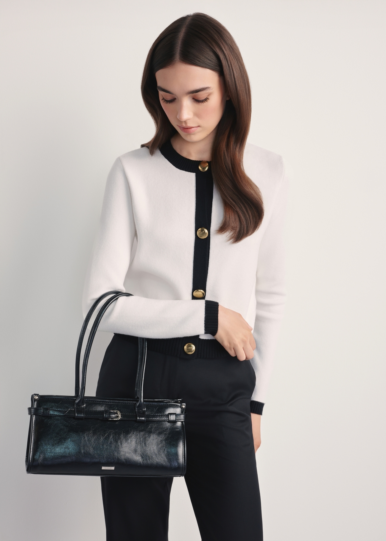 Czarna elegancka torebka damska TOREC-1065-99(Z25)- widok produktu z przodu na modelce, na białym tle. Widoczna sylwetka do kolan.