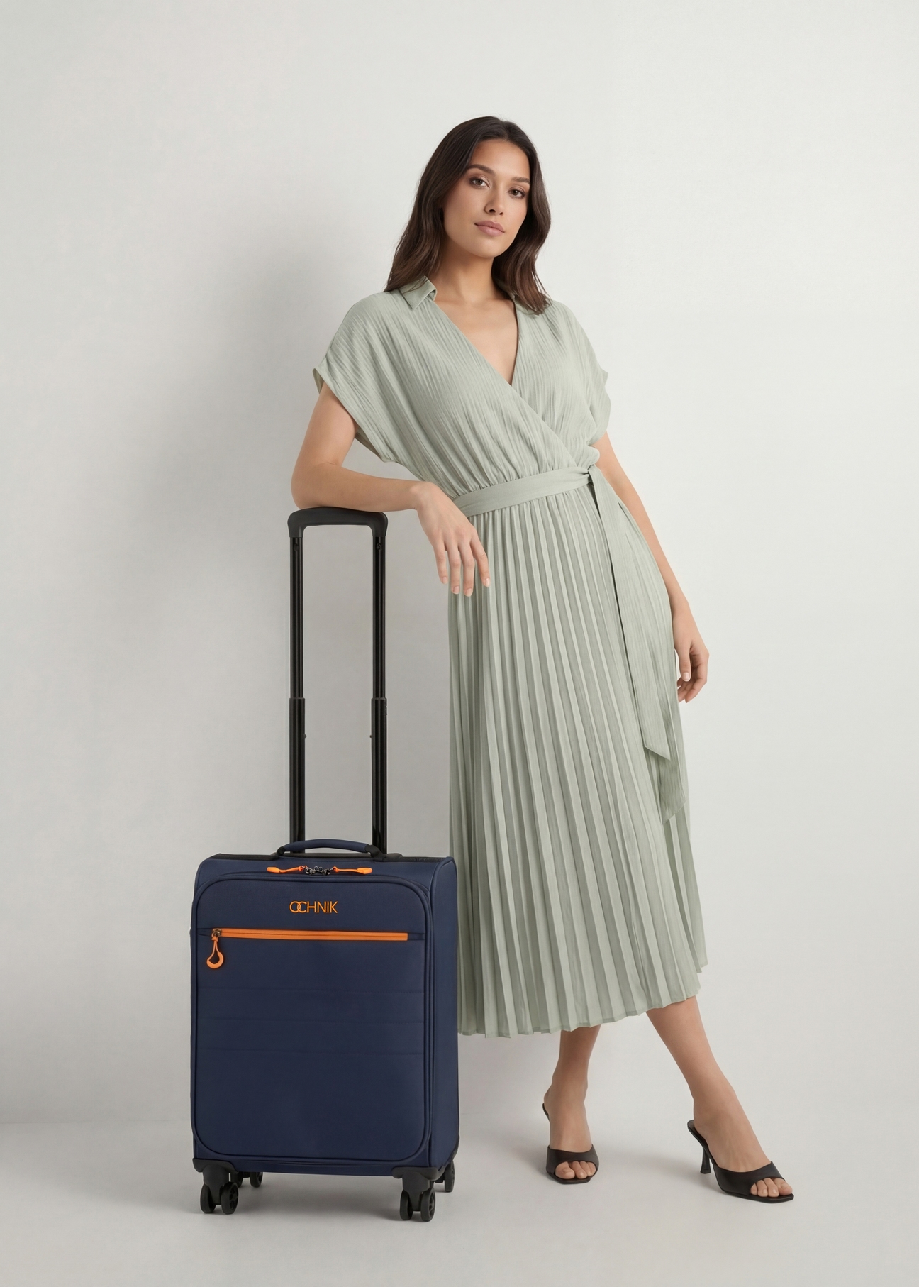 Walizka średnia na kółkach WALNY-0045-7D-24(W26), widok produktu z przodu obok sylwetki modelki.