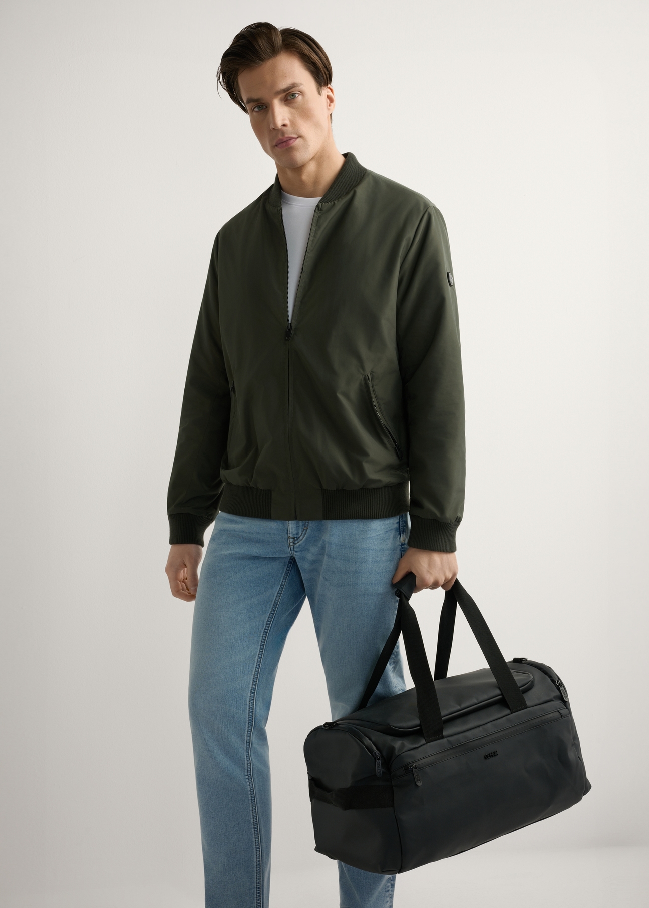 Czarna torba podróżna TORMN-0412-99(W26), widok produktu w ręce modela. Widoczna cała sylwetka.