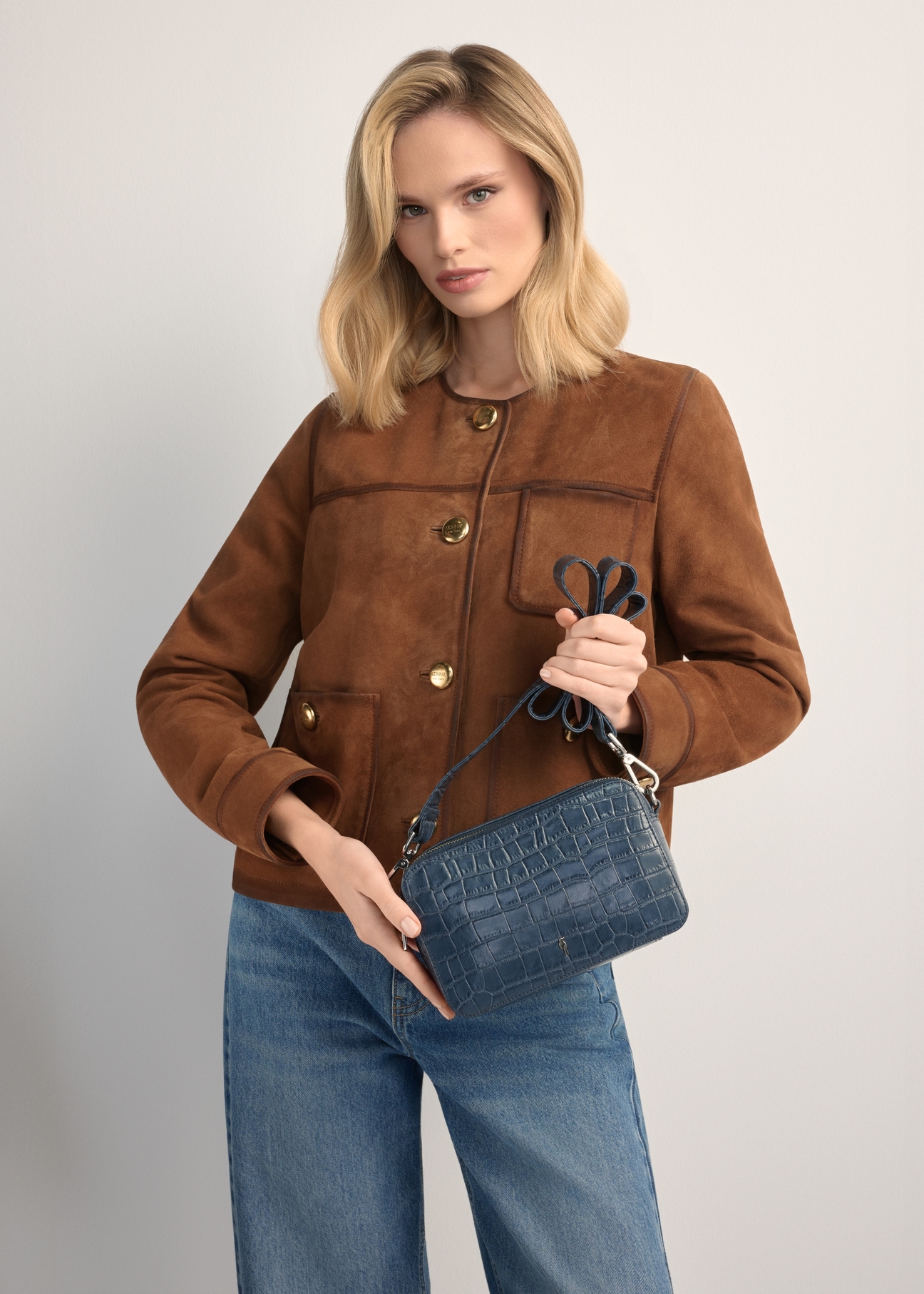 Mała granatowa skórzana torebka croco TORES-1231-7D(W26), widok produktu w rękach modelki. Widoczna połowa sylwetki.