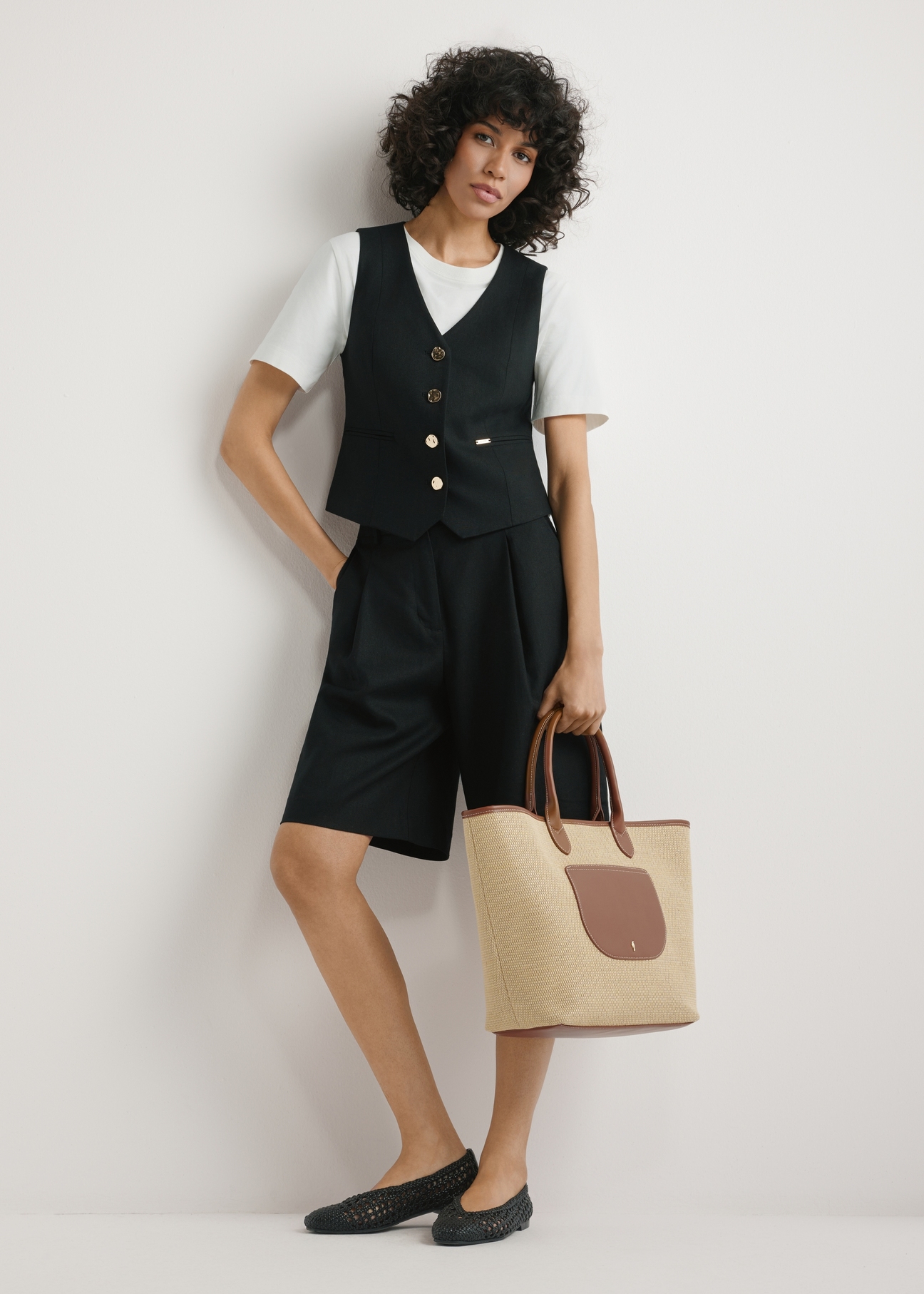 Słomkowa duża torebka damska TOREC-1229-1E(W26),widok produktu trzymanego przez modelkę w ręku, na jasnym tle. Widoczna cała sylwetka. 