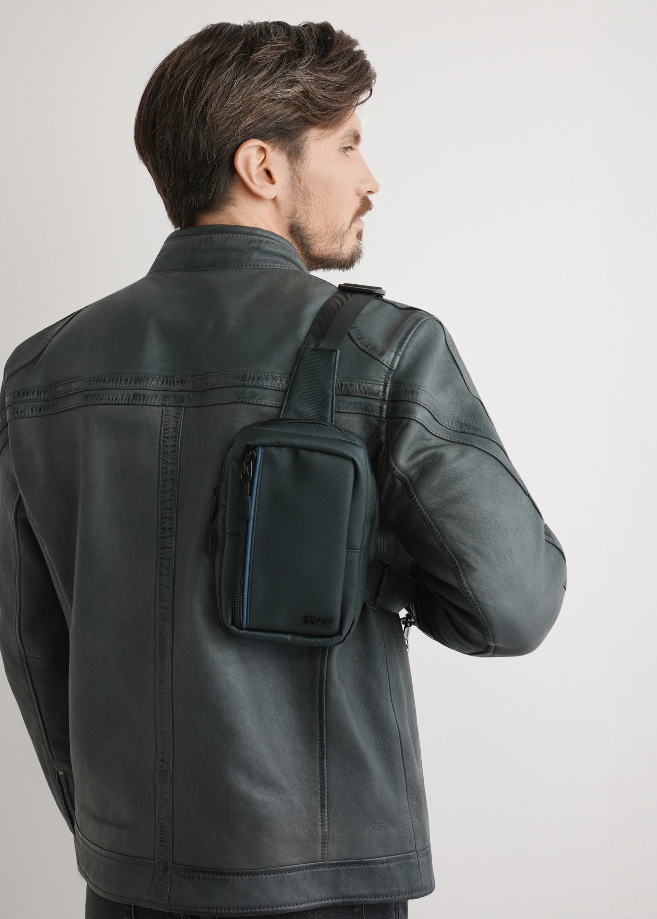 Czarna męska saszetka na ramię TORMN-0393-9J(W26) - widok produktu z przodu, na modelu, stojącym tyłem, na jasnym tle. Widoczna połowa sylwetki.