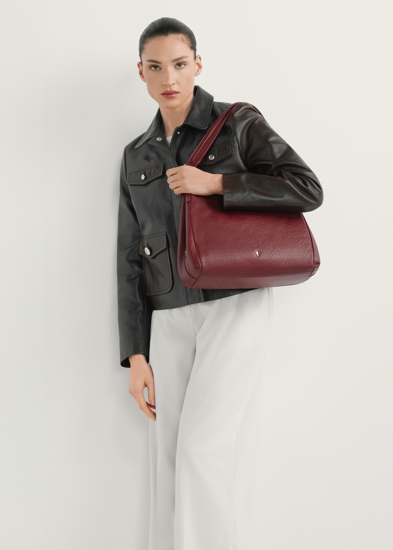 Ciemnoczerwona skórzana damska torebka shopper TORES-0636D-4C(W26) - widok produktu lekko po skosie, na modelce, na jasnym tle. Widoczna cała cała sylwetka.