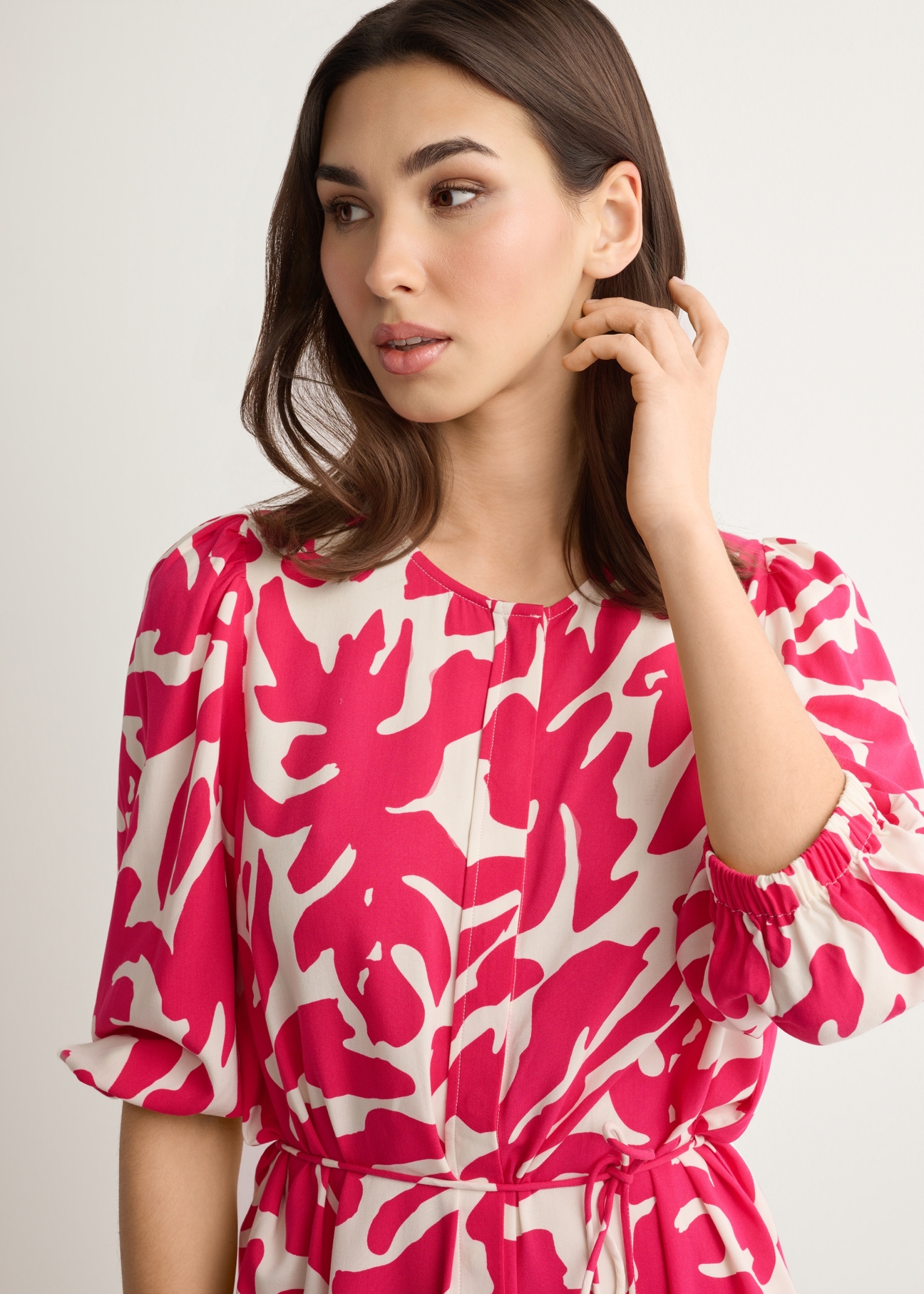 Sukienka w różowe kwiaty z wiskozy SUKDT-0271-5P(W26), widok produktu z przodu na modelce. Widoczna połowa sylwetki.