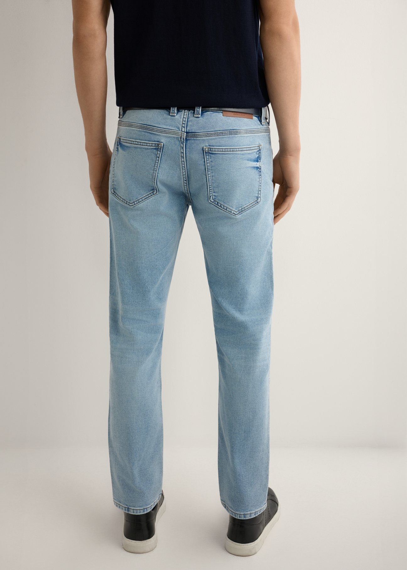 Niebieskie spodnie jeansowe męskie JEAMT-0021-7B(W26), widok produktu z tyłu na modelu. Widocza połowa sylwetki.