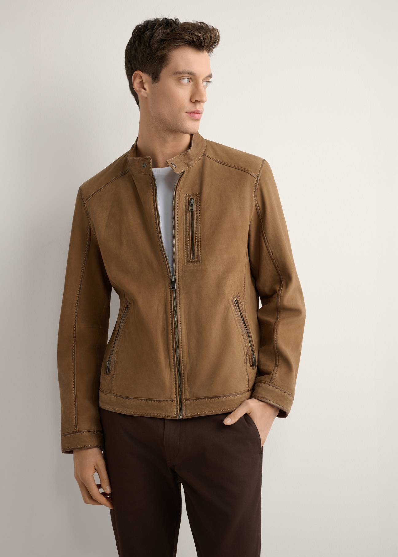 Ciemnobeżowa kurtka zamszowa męska KURMS-0398-1C(W26) - widok produktu z przodu, na modelu, na jasnym tle. Widoczna sylwetka do kolan. 