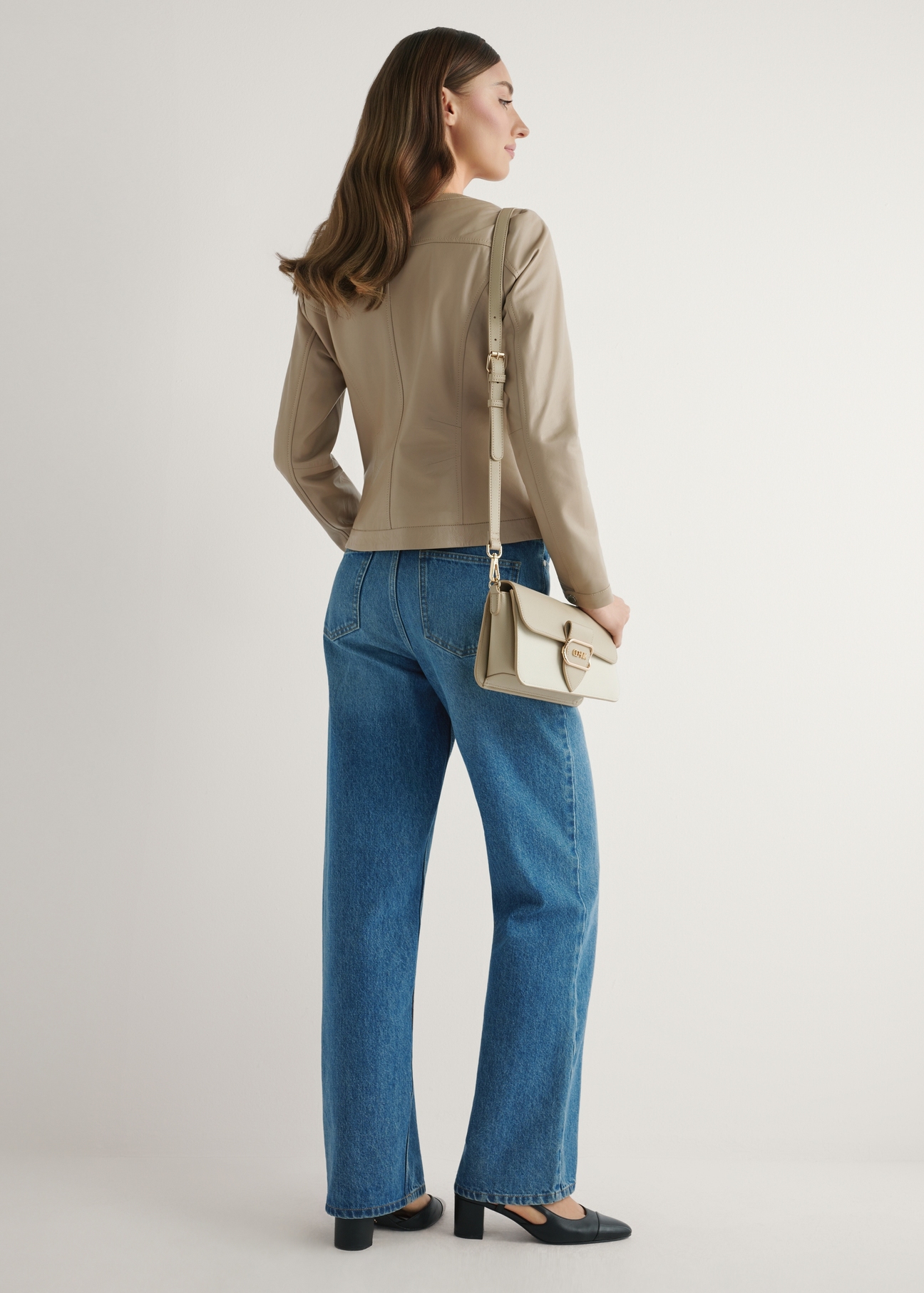 Kremowa torebka listonoszka damska TOREC-1120-0P(W26) - widok produktu lekko po skosie, na modelce, na jasnym tle. Widoczna cała sylwetka. 