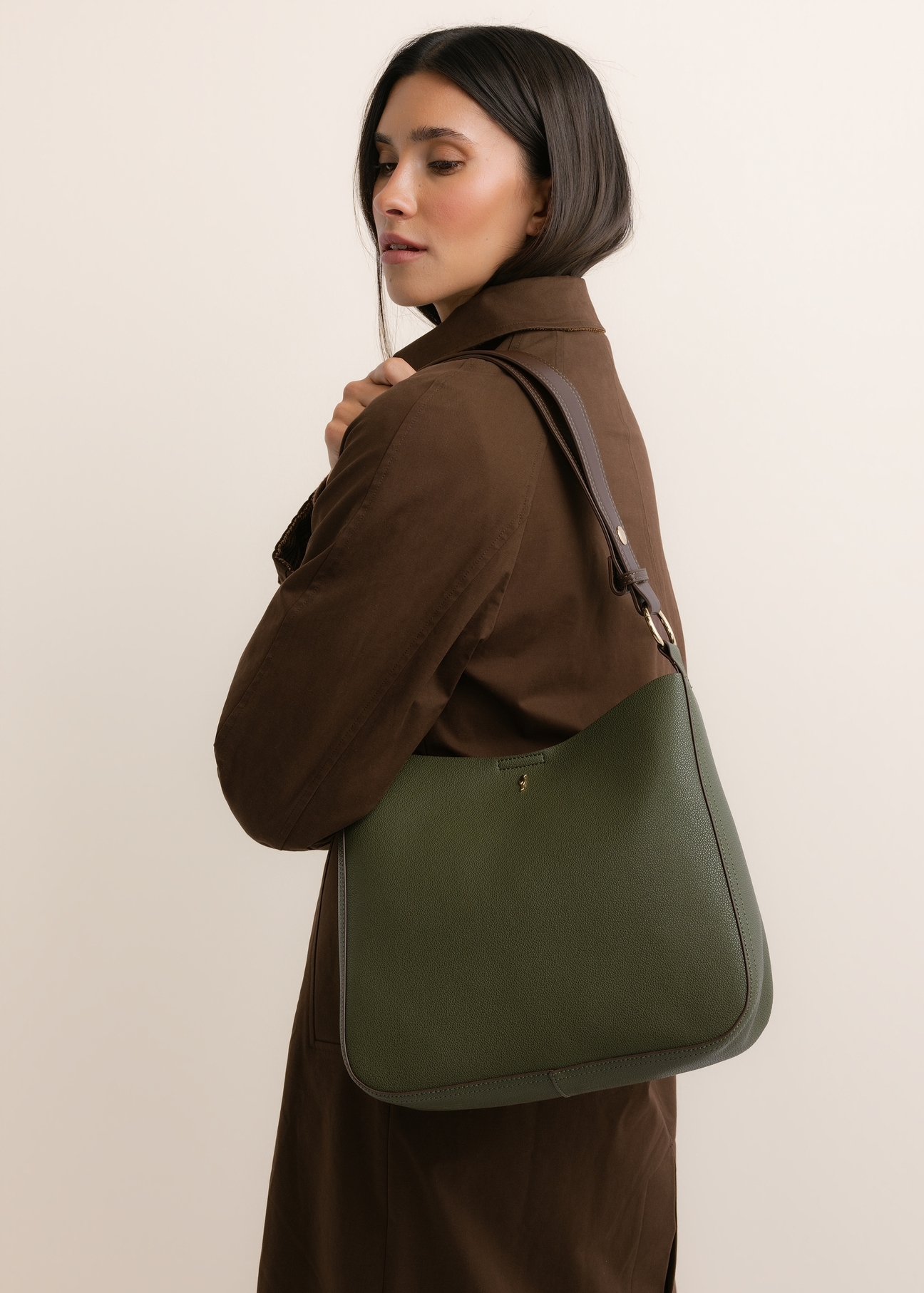 Zielona torebka damska hobo TOREC-1257-8B(Z26), widok skosu produktu, na modelce, na jasnym tle. Widoczna połowa sylwetki. 