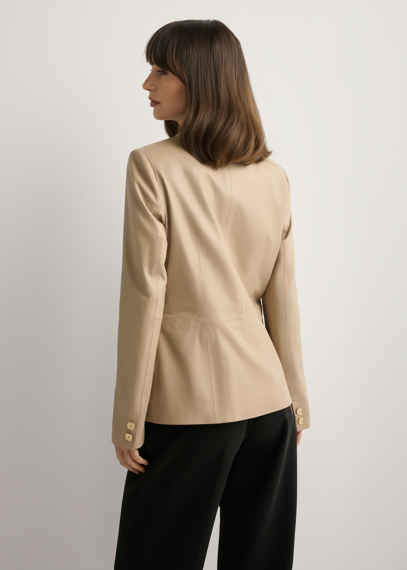 Beżowa skórzana marynarka damska KURDS-0445-1B(W26), widok produktu z tyłu na modelce. Widoczna połowa sylwetki.