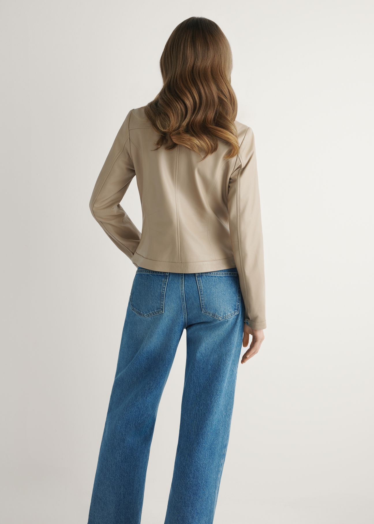 Beżowa kurtka damska ze skóry naturalnej KURDS-0154-1B(W26), widok produktu z tyłu na modelce. Widoczna połowa sylwetki.