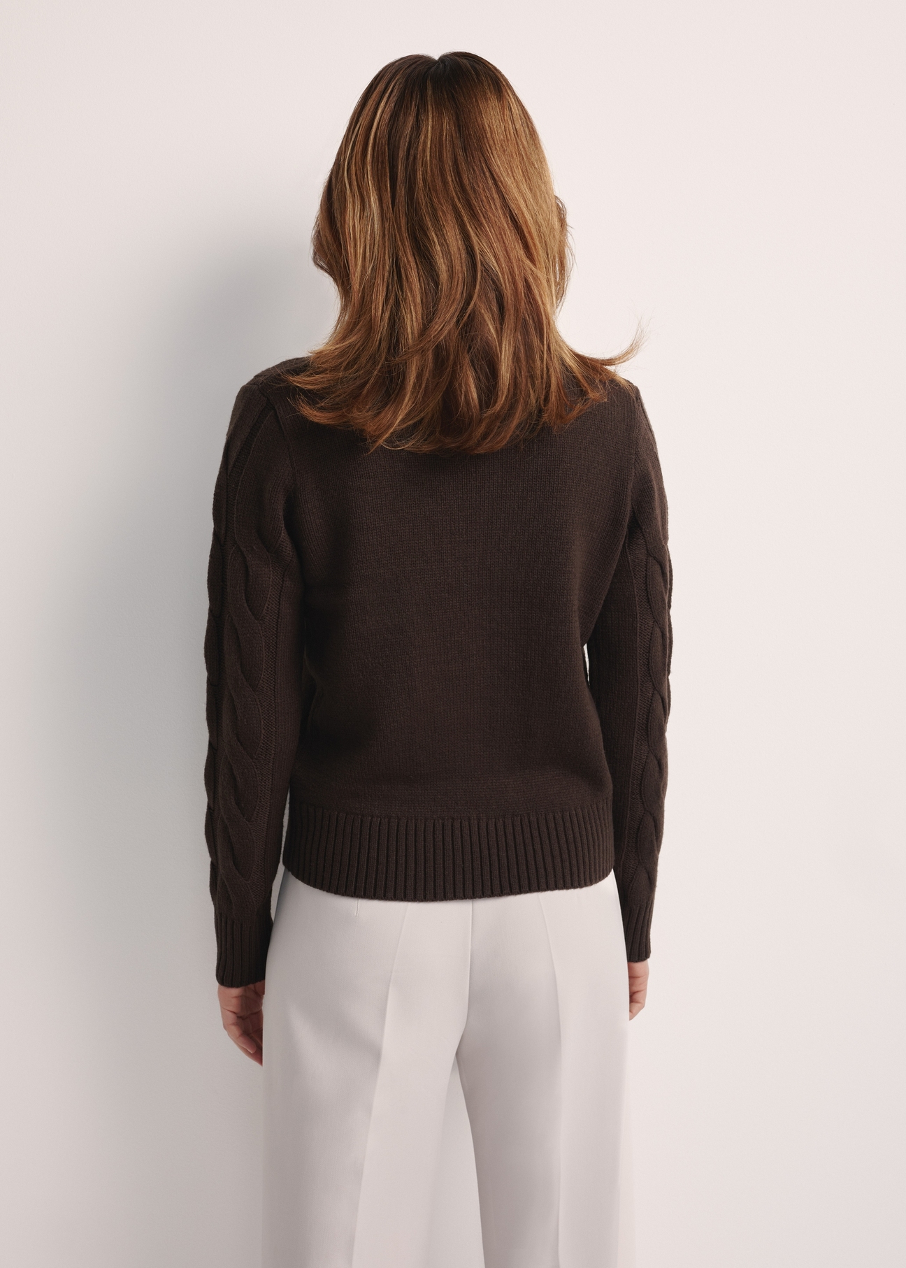 Czekoladowy sweter damski z ozdobnym splotem SWEDT-0210-90(Z25), widok produktu z tyłu na modelce. Widoczna połowa sylwetki.