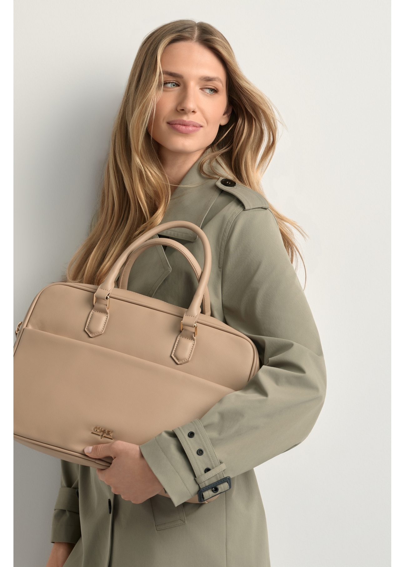 Beżowa torba na laptopa damska TOREC-1209-1B(W26), widok produktu w rękach modelki. Widoczna połowa sylwetki.