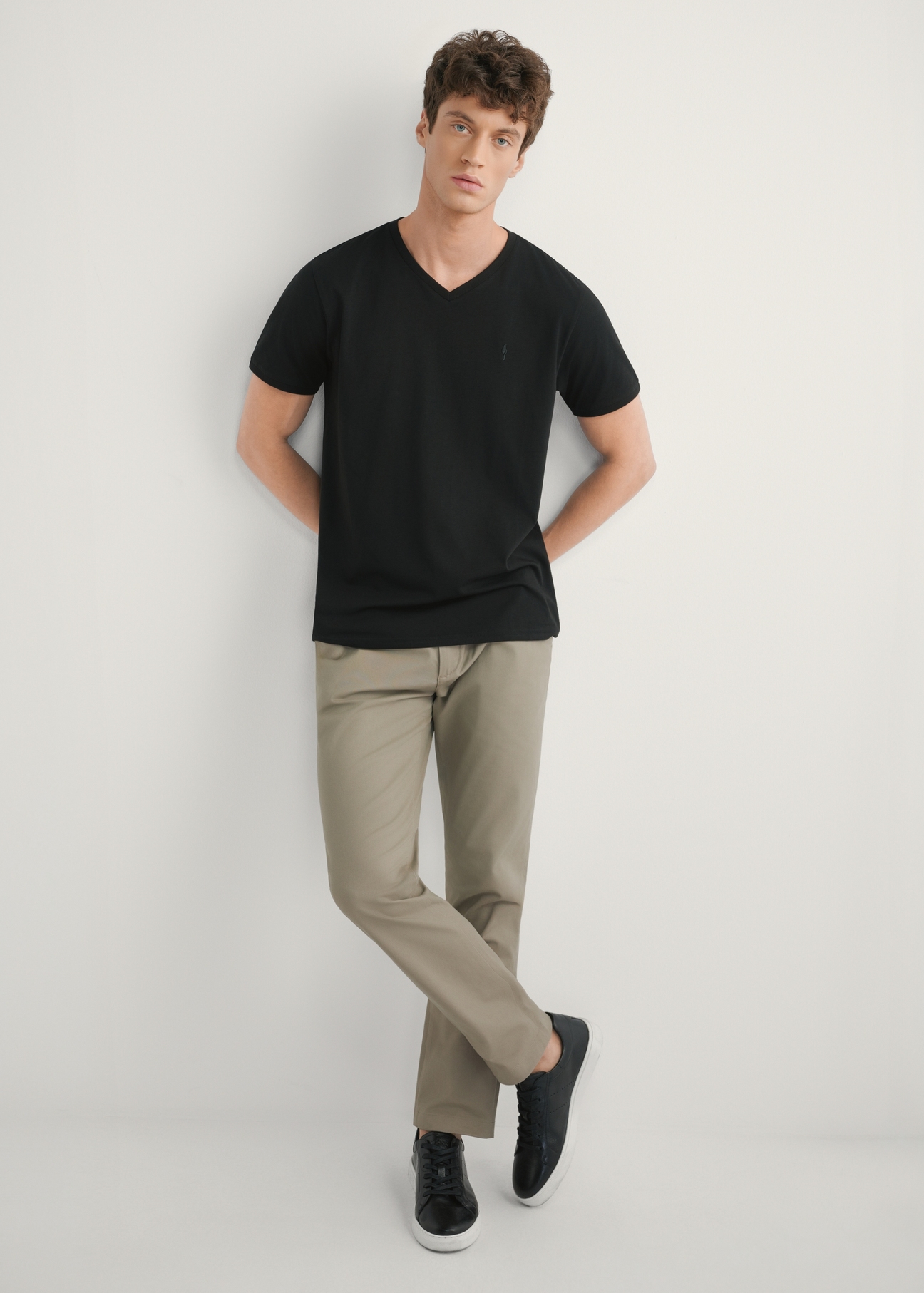 Ciemnobeżowe spodnie męskie SPOMT-0121-1K(W26)- widok produktu z przodu, na modelu, na jasnym tle. Widoczna cała sylwetka.