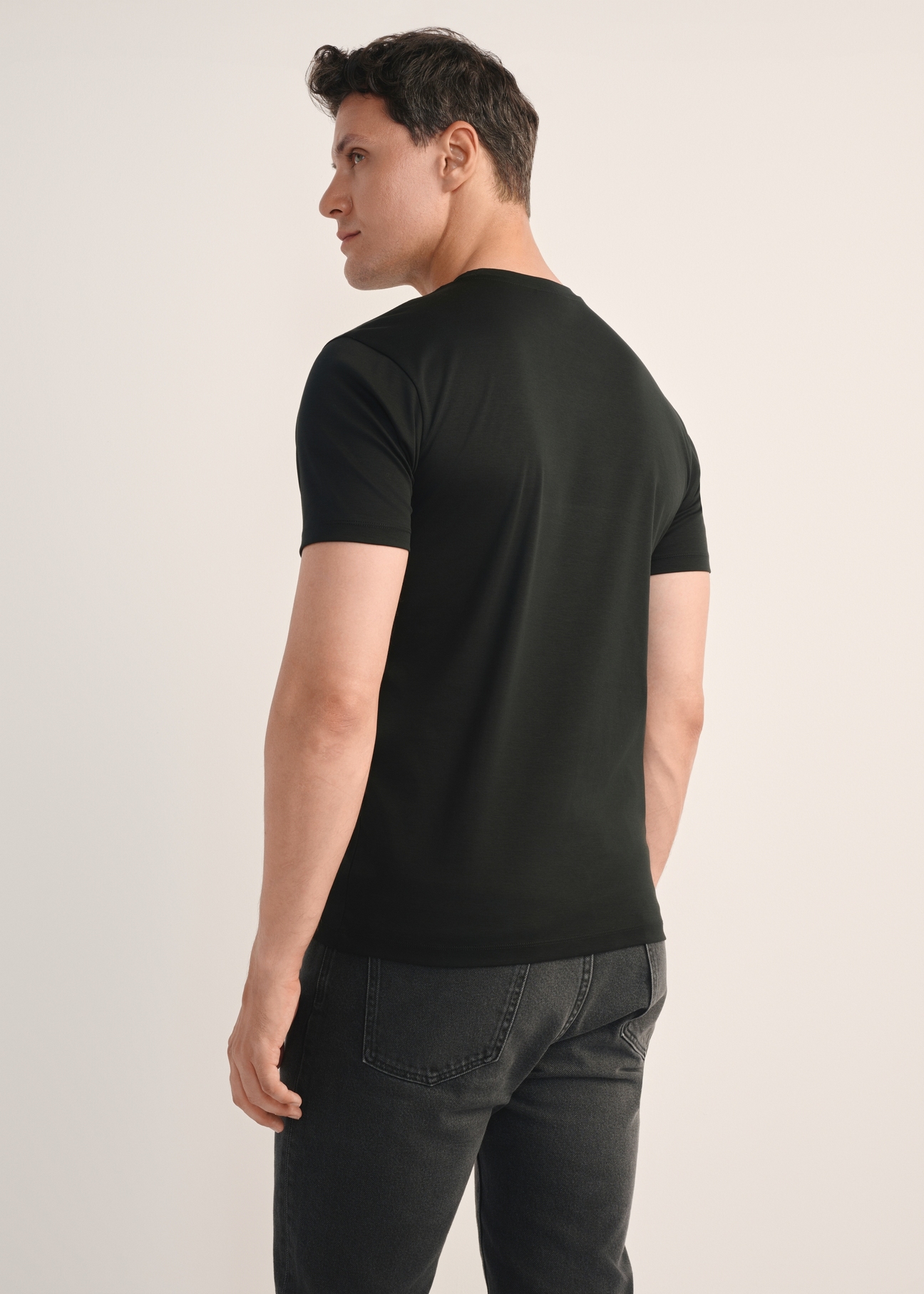 Czarny T-shirt męski z bawełny merceryzowanej TSHMT-0135-99(Z25), widok produktu z tyłu na modelu. Widoczna połowa sylwetki.