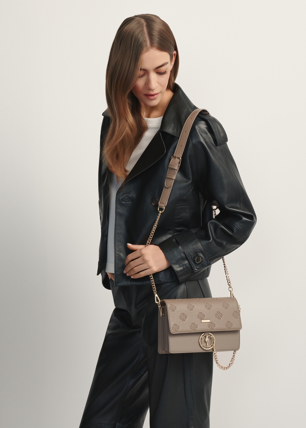 Ciemnobeżowa torebka damska z monogramem TOREC-0536-1K(W26), widok produktu od przodu na modelce, widoczna połowa sylwetki.