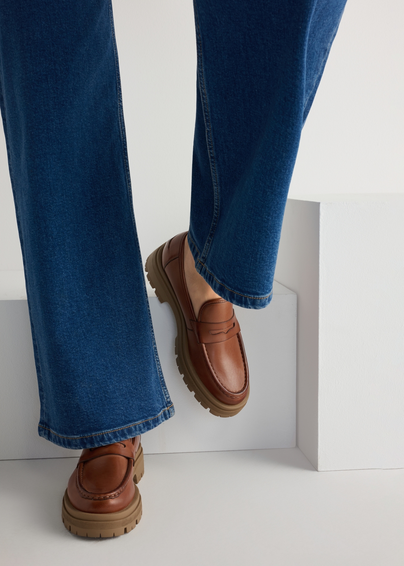Skórzane mokasyny na platformie w kolorze koniaku BUTYD-1069-1F(W26), widok produktu od przodu na modelce, widoczna połowa sylwetki.