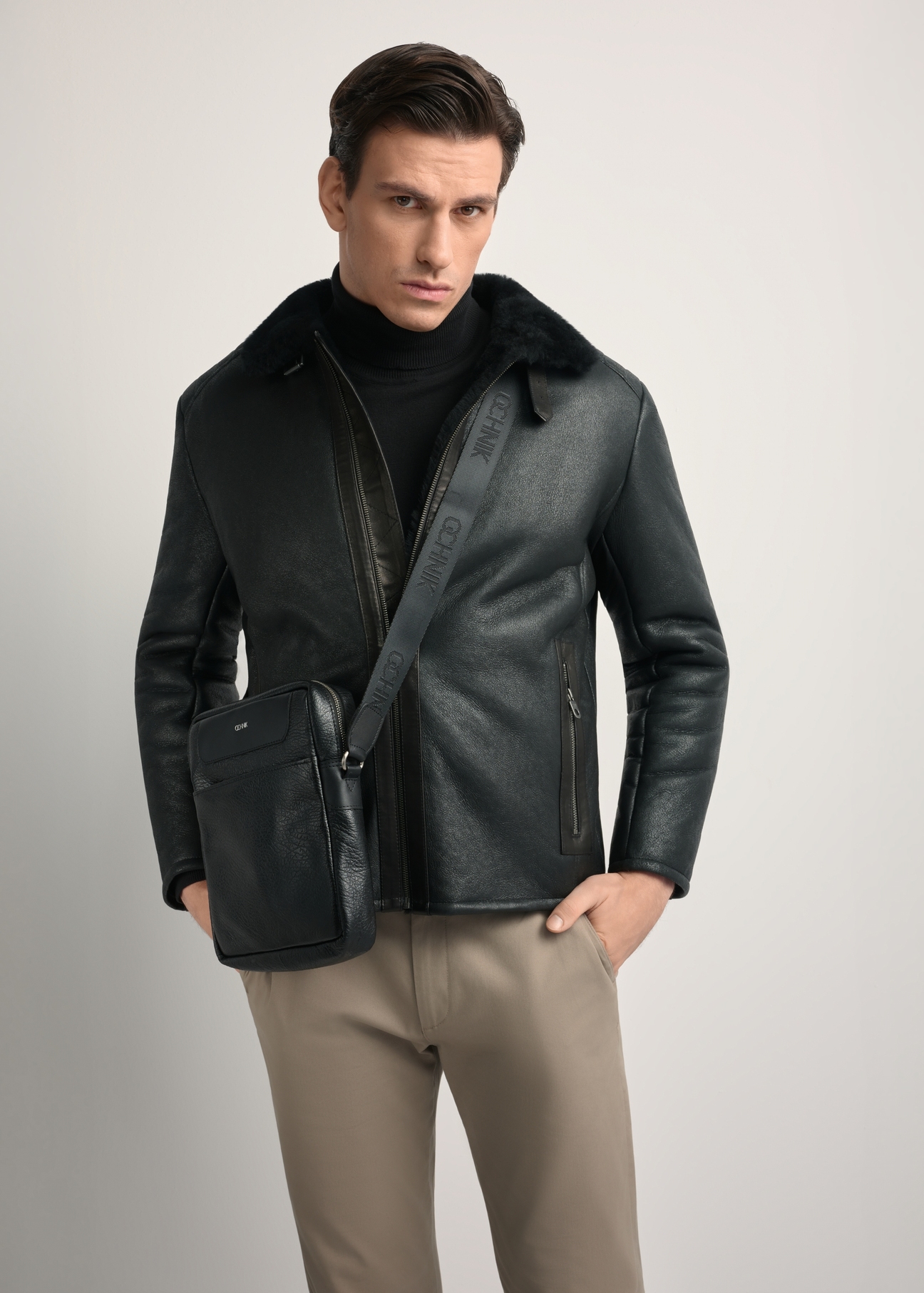 Czarna skórzana torba męska z logo TORMS-0297A-99(Z25) - widok produktu po skosie, na modelu, na białym tle. Widoczna sylwetka do kolan.