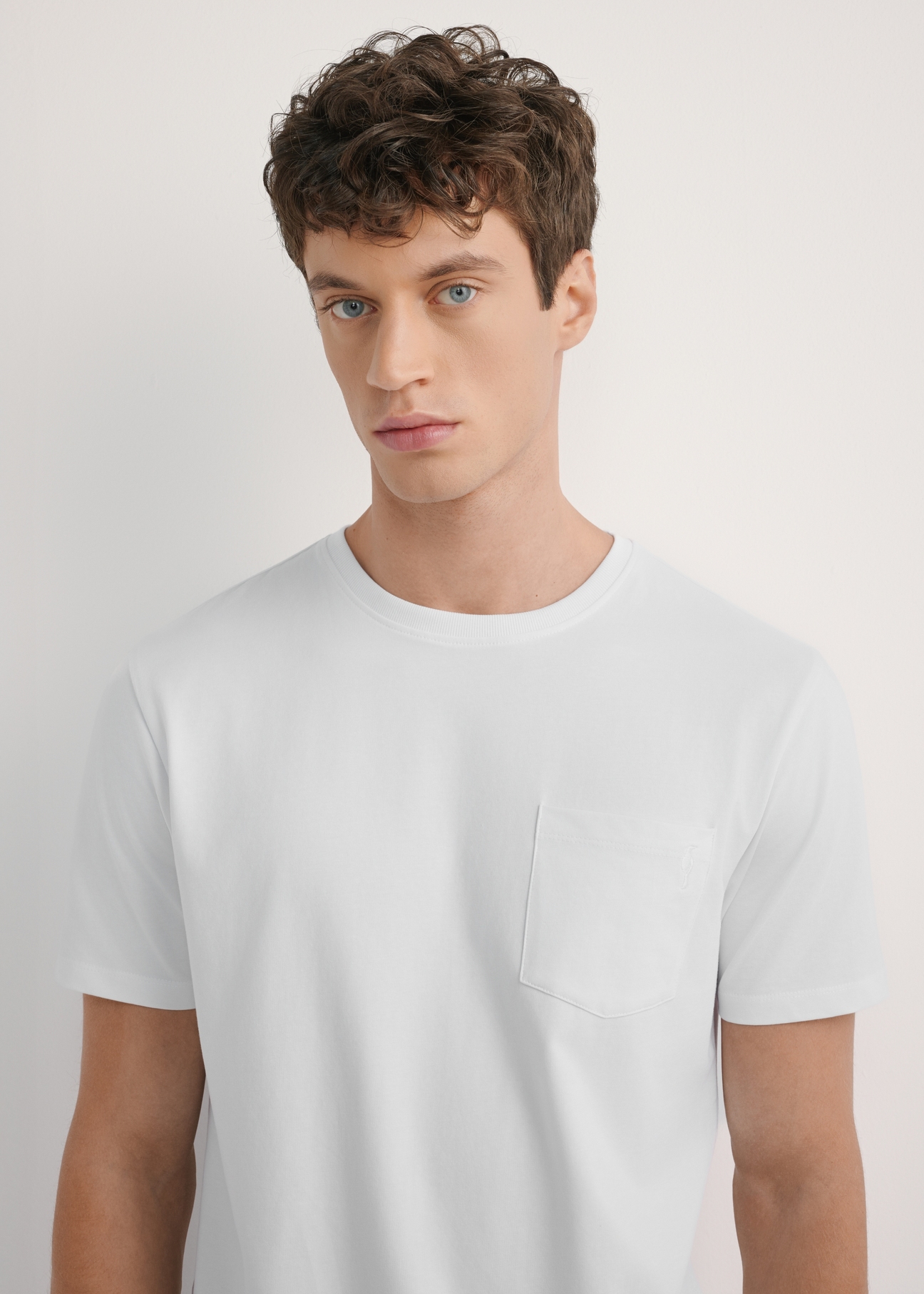 Biały T-shirt męski TSHMT-0137-0A(W26) - widok produktu z przodu, na modelu, na jasnym tle. Widoczna połowa sylwetki. 