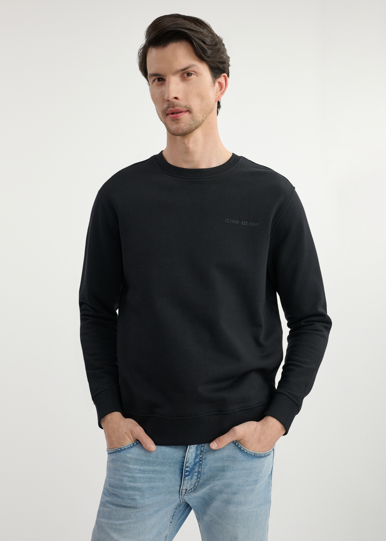Czarna bluza męska bez kaptura BLZMT-0070-99(W25) - widok z przodu na modelu na białym tle. Widoczna połowa sylwetki. 