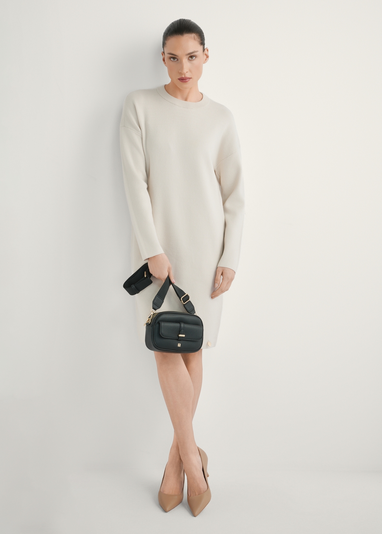 Mała czarna torebka damska TOREC-1174-99(W26), widok produktu w dłoni modelki. Widoczna cała sylwetka.