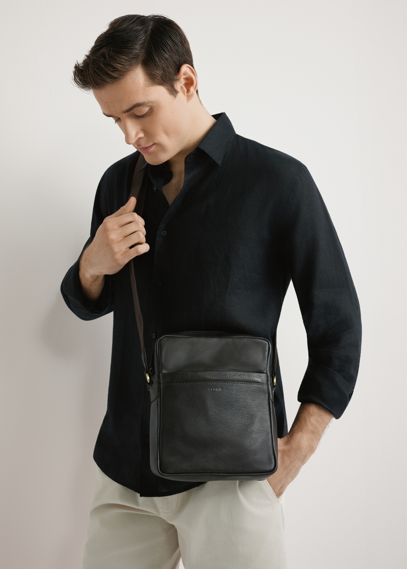 Skórzana torba męska w kolorze ciemnobrązowym TORMS-0502-1I(W26) - widok produktu z przodu, na modelu, na jasnym tle. Widoczna połowa sylwetki. 