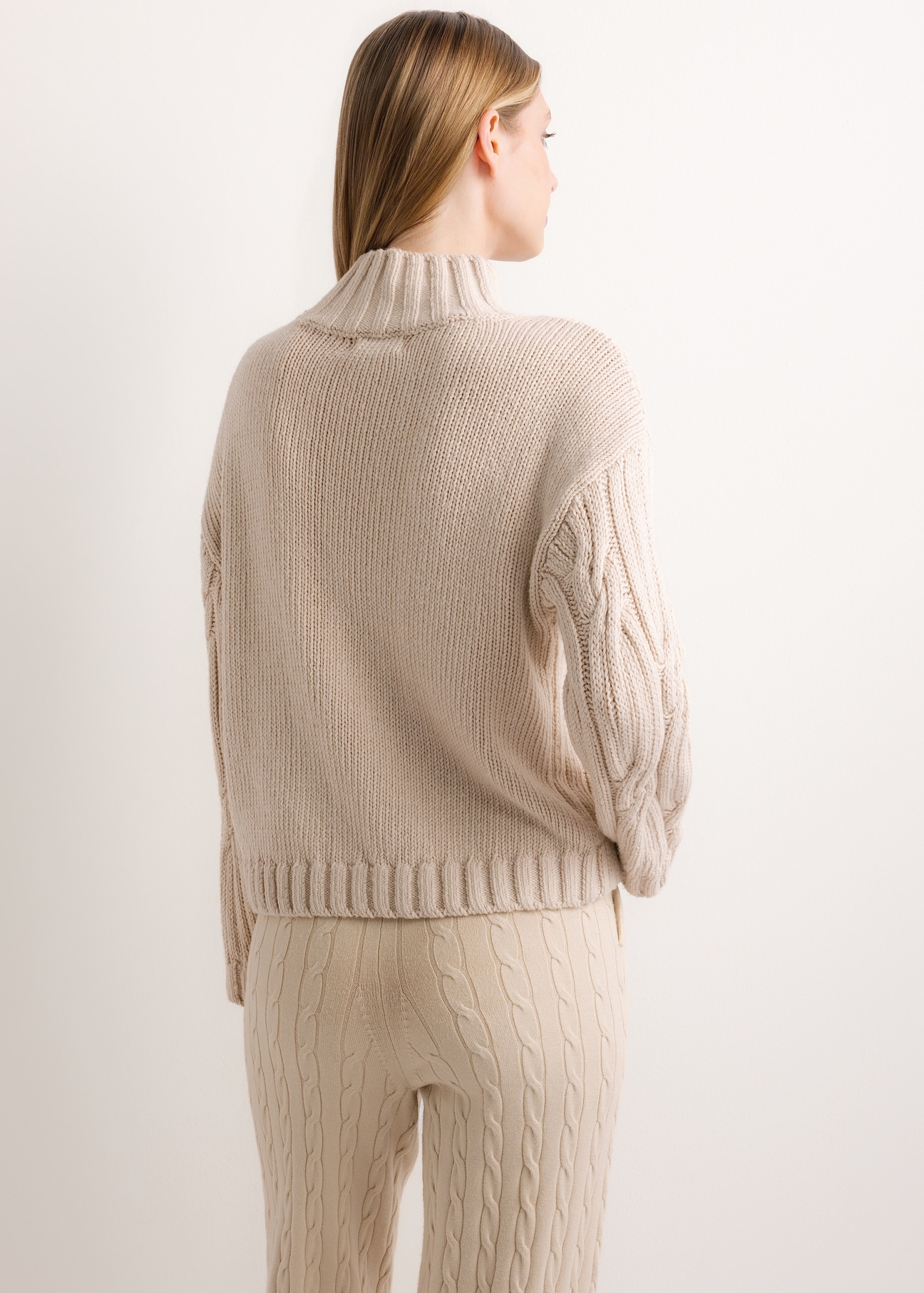 Damski sweter oversize w jasnobeżowym kolorze SWEDT-0278-1A(Z26), widok produktu od tyłu na modelce. Widoczna połowa sylwetki.