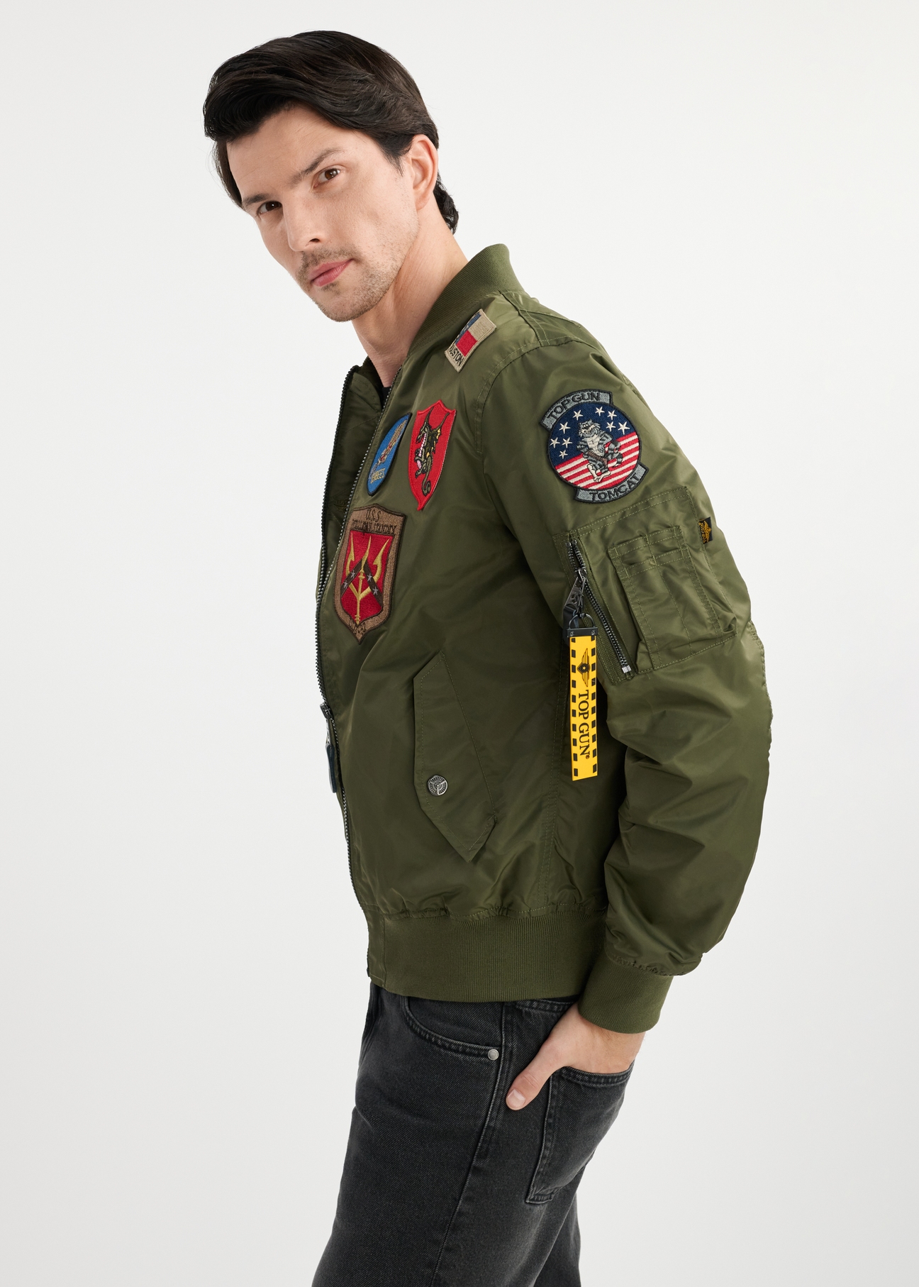Oliwkowa męska kurtka pilotka TOP GUN KURMT-0381-57(W25) - widok z boku na modelu na białym tle. Widoczna połowa sylwetki. 
