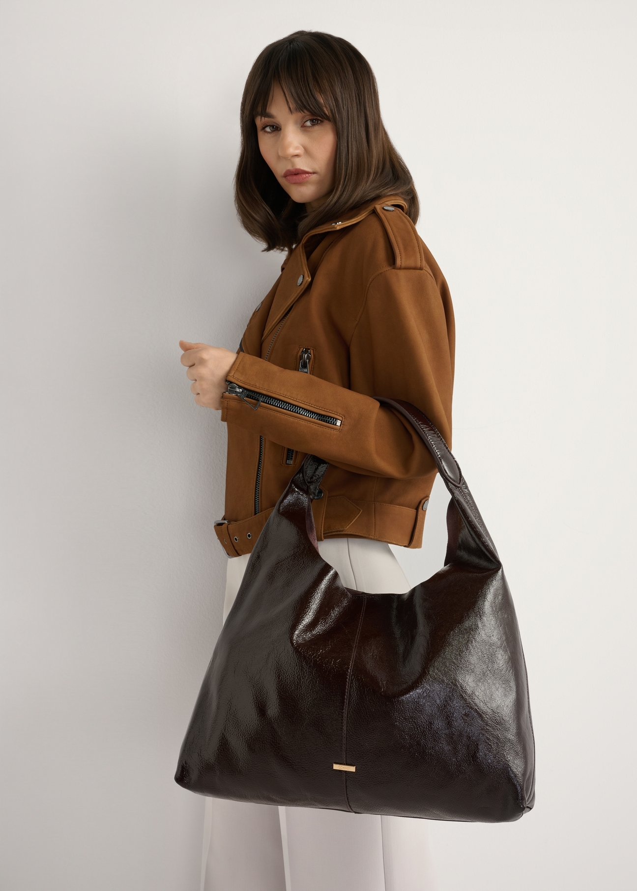 Duża skórzana brązowa torebka damska TORES-1179-1I(W26), widok produktu na ramieniu modelki. Widoczna połowa sylwetki.