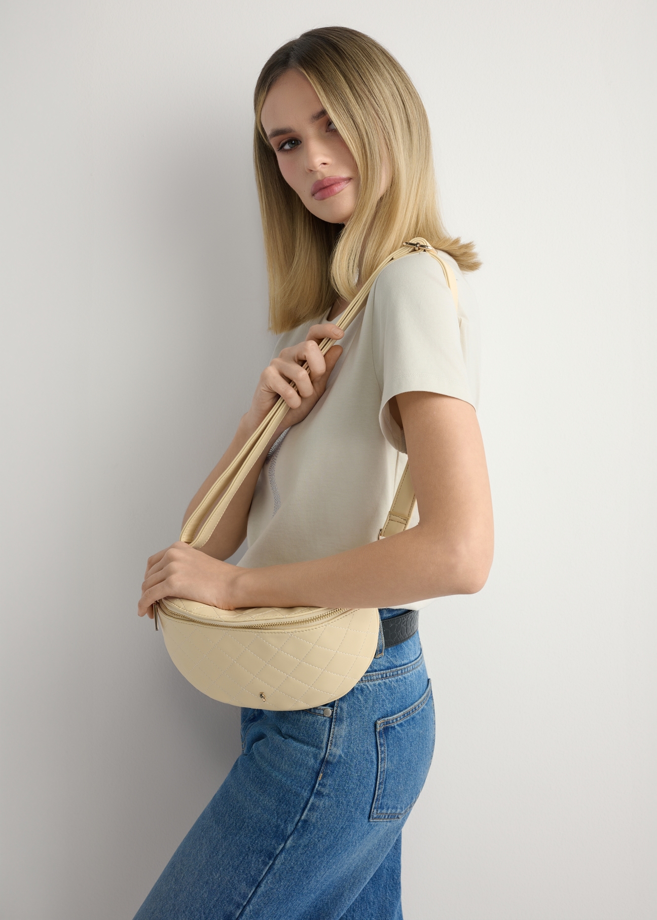 Pikowana jasnożółta nerka damska TOREC-0878-2A(W26), widok produktu na ramieniu modelki. Widoczna połowa sylwetki.